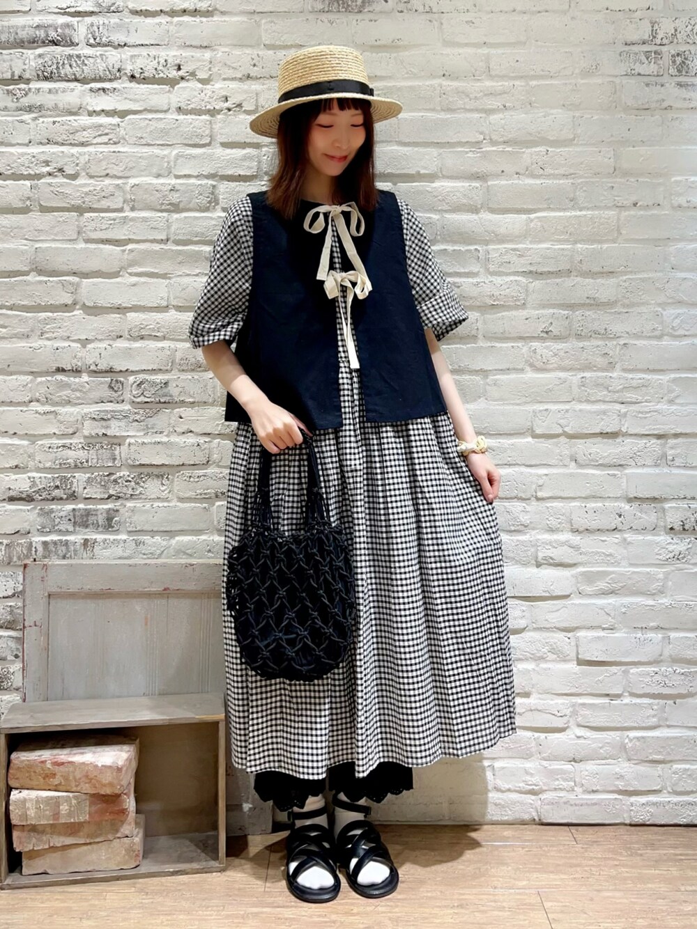 ブラック系のベスト、ブラック系のハンドバッグ、ホワイト系のワンピースを着用したレディースの秋コーディネートの1枚目の写真