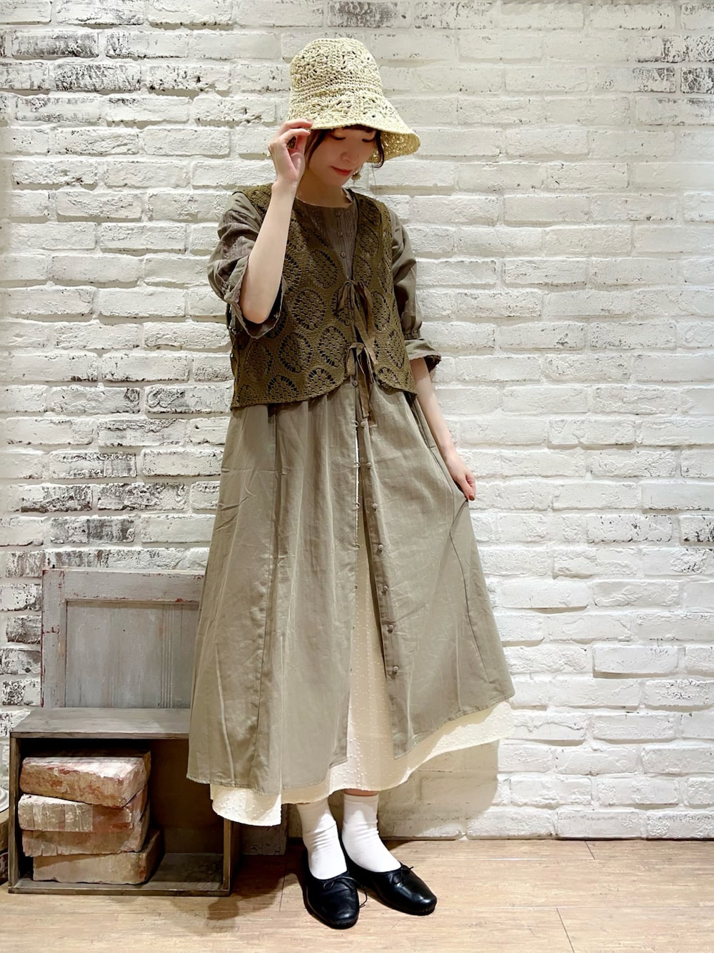 グリーン系のベスト、グリーン系のワンピース、ホワイト系のスカートを着用したレディースの秋コーディネートの1枚目の写真