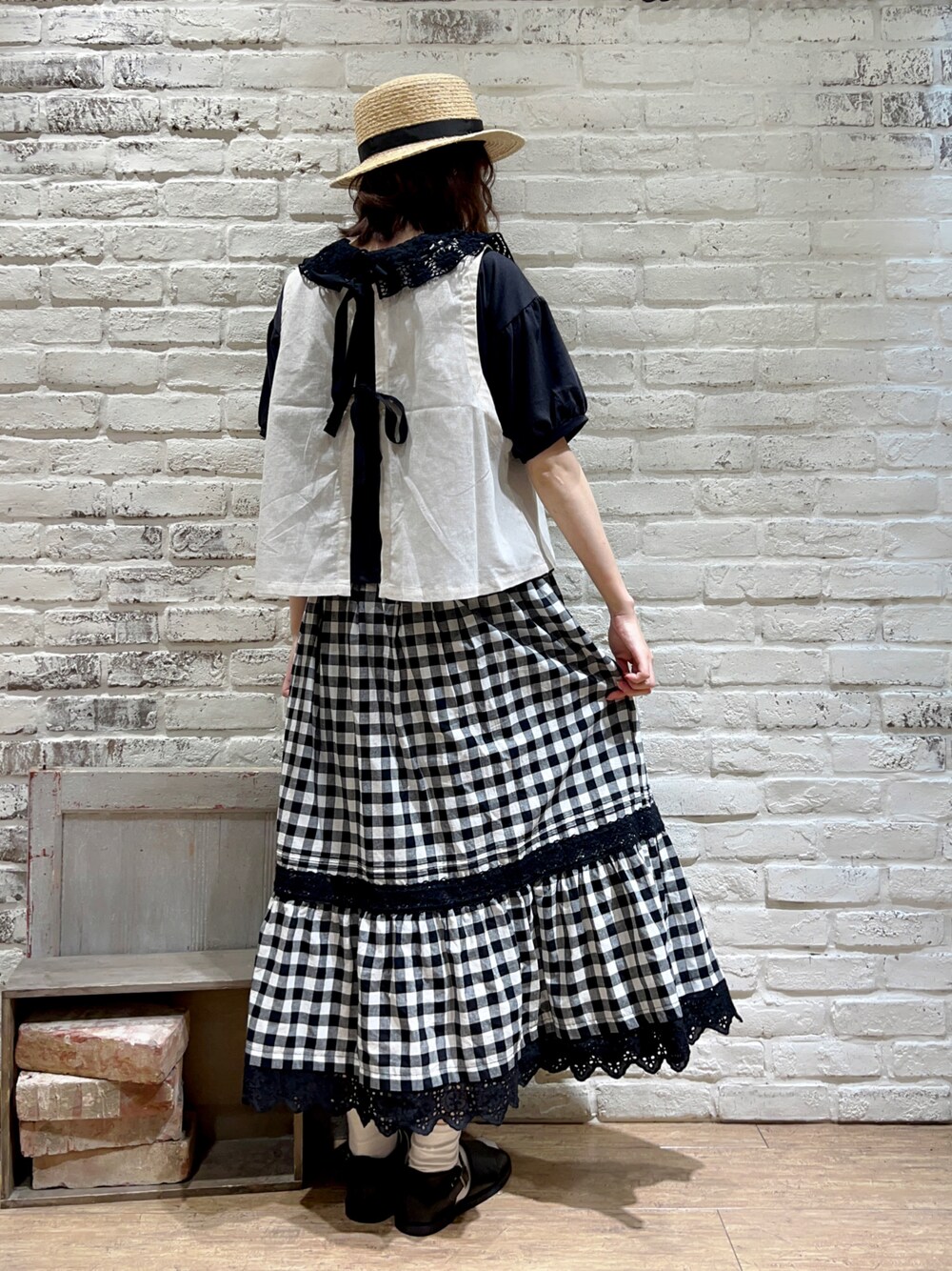 グレー系のTシャツ/カットソー、ホワイト系のベスト、ブラック系のスカートを着用したレディースの秋コーディネートの1枚目の写真