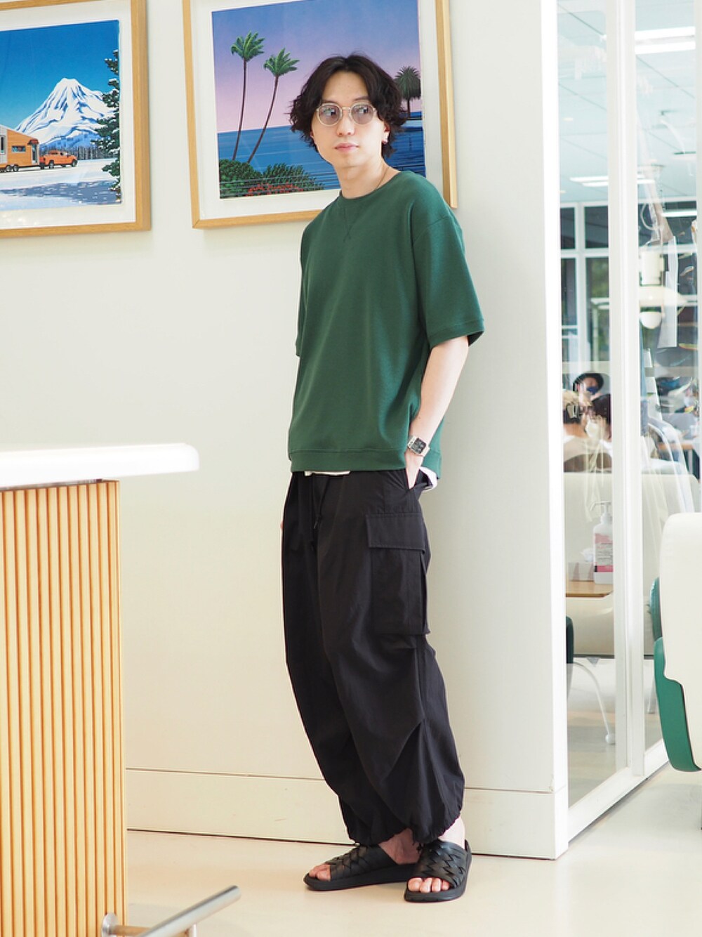 グリーン系のTシャツ/カットソー、ブラック系のカーゴパンツ、ブラック系のサンダルを着用したメンズの春コーディネートの1枚目の写真