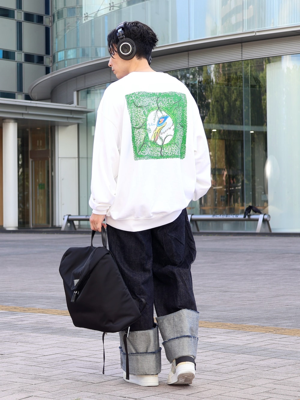 ブルー系のデニムパンツ、ブラック系のバックパック/リュック、ホワイト系のスニーカーを着用したメンズの冬コーディネートの1枚目の写真