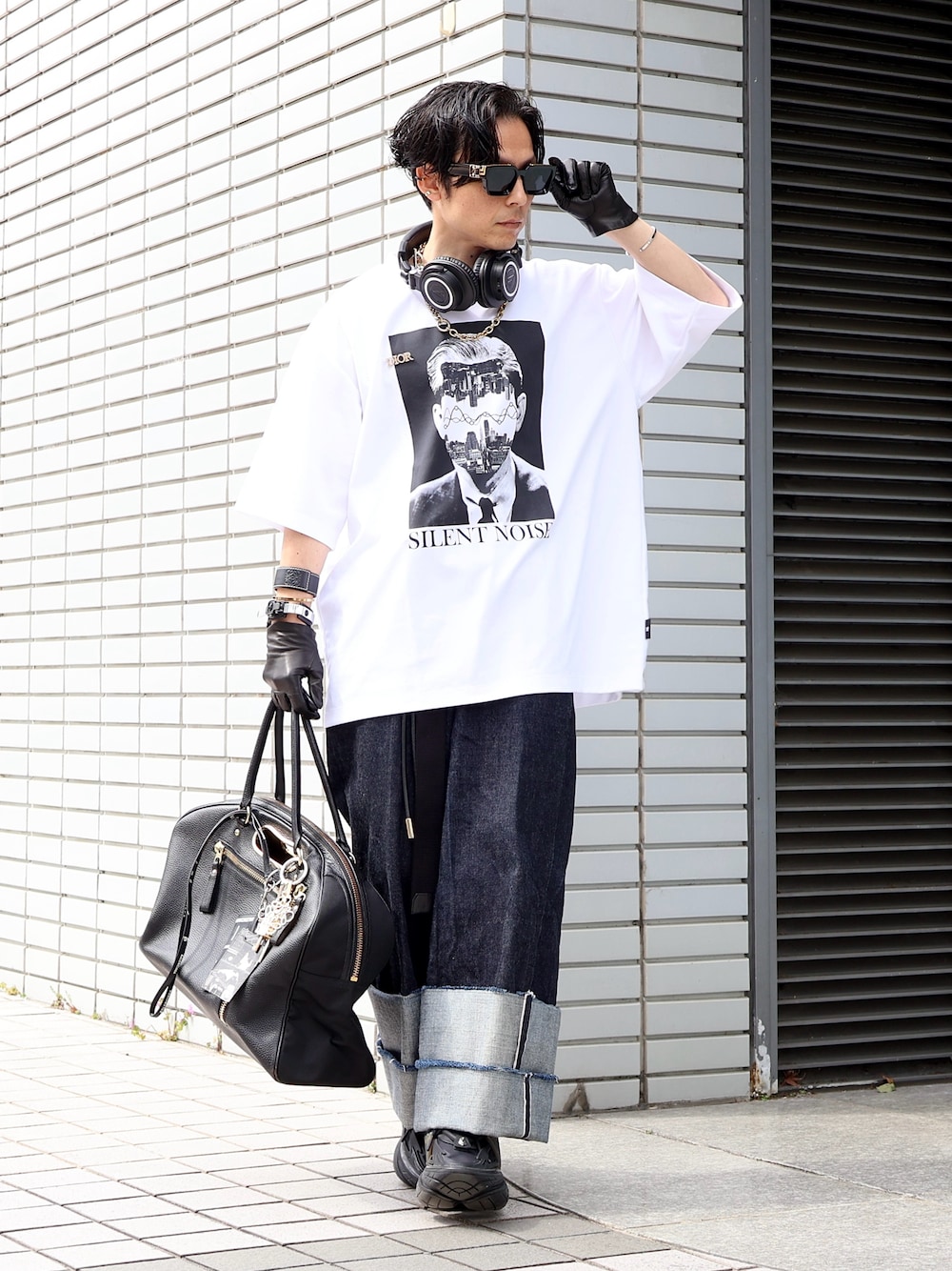 ブラック系のスニーカー、ブルー系のデニムパンツ、ブラック系のボストンバッグを着用したメンズの秋コーディネートの1枚目の写真