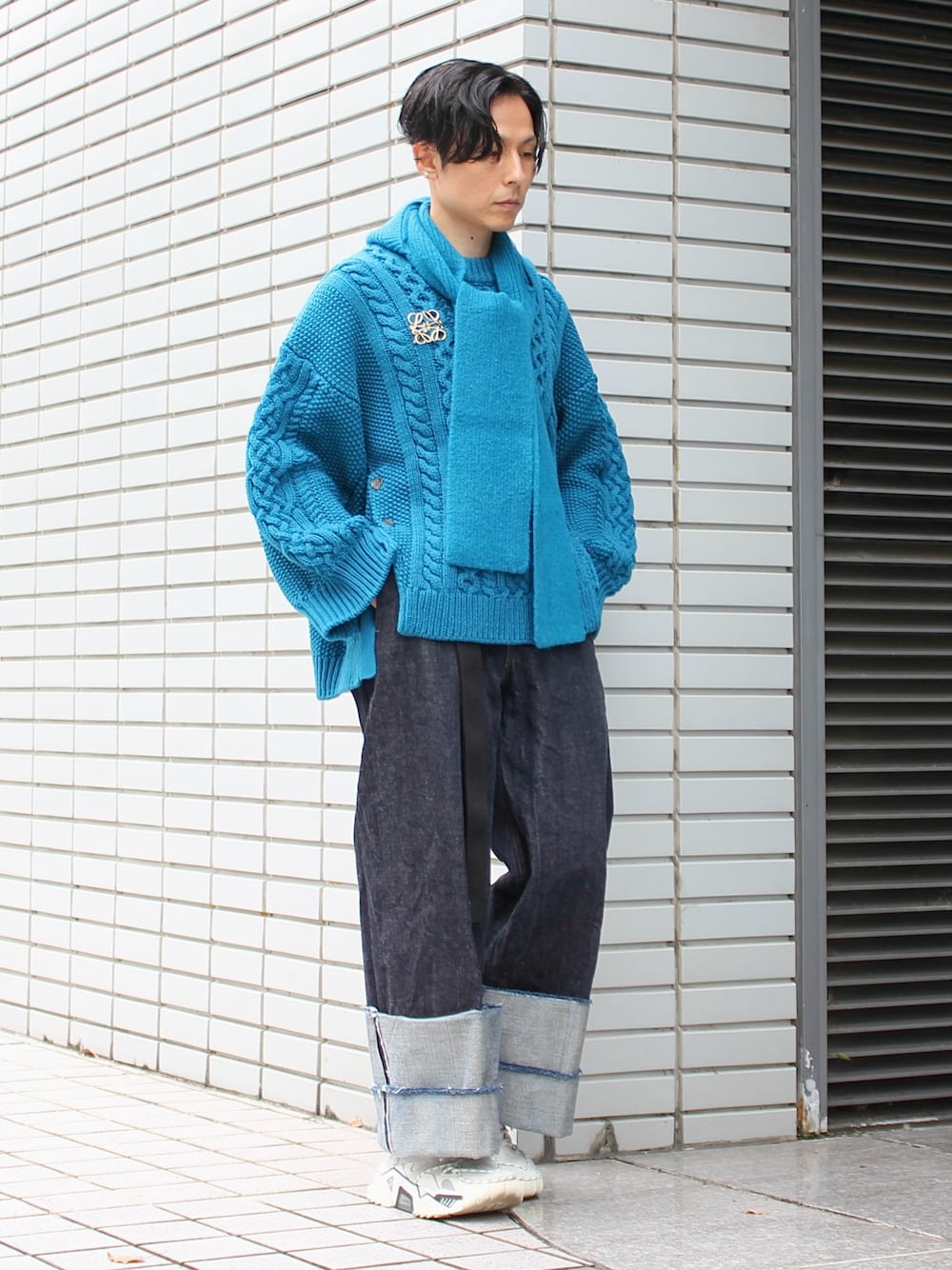 ブルー系のデニムパンツ、ホワイト系のスニーカー、ゴールド系のブローチ/コサージュを着用したメンズの冬コーディネートの1枚目の写真