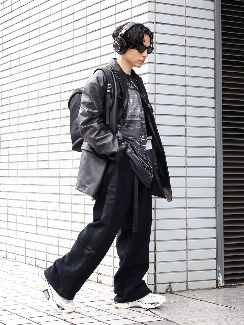 ブラック系のテーラードジャケット、ホワイト系のスニーカー、ブラック系のバックパック/リュックを着用したメンズの冬コーディネートの1枚目の写真