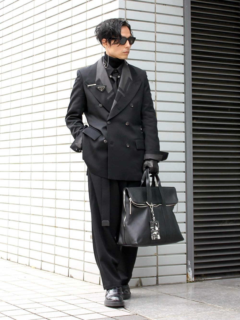 ブラック系のハンドバッグ、ブラック系のドレスシューズ、ブラック系のサングラスを着用したメンズの春コーディネートの1枚目の写真