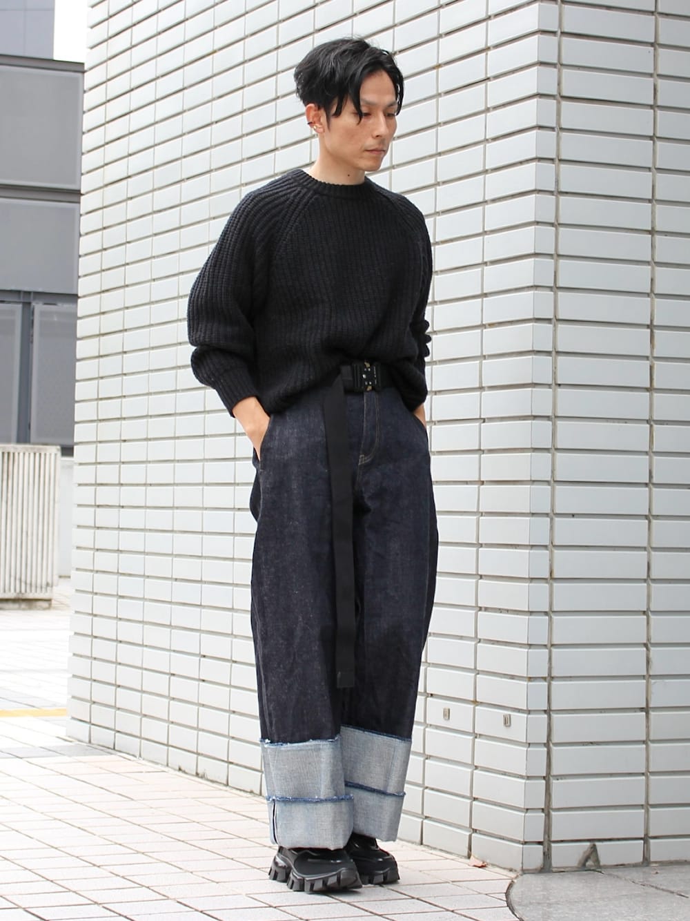 ブラック系のスニーカー、ブルー系のデニムパンツ、ブラック系のニット/セーターを着用したメンズの春コーディネートの1枚目の写真