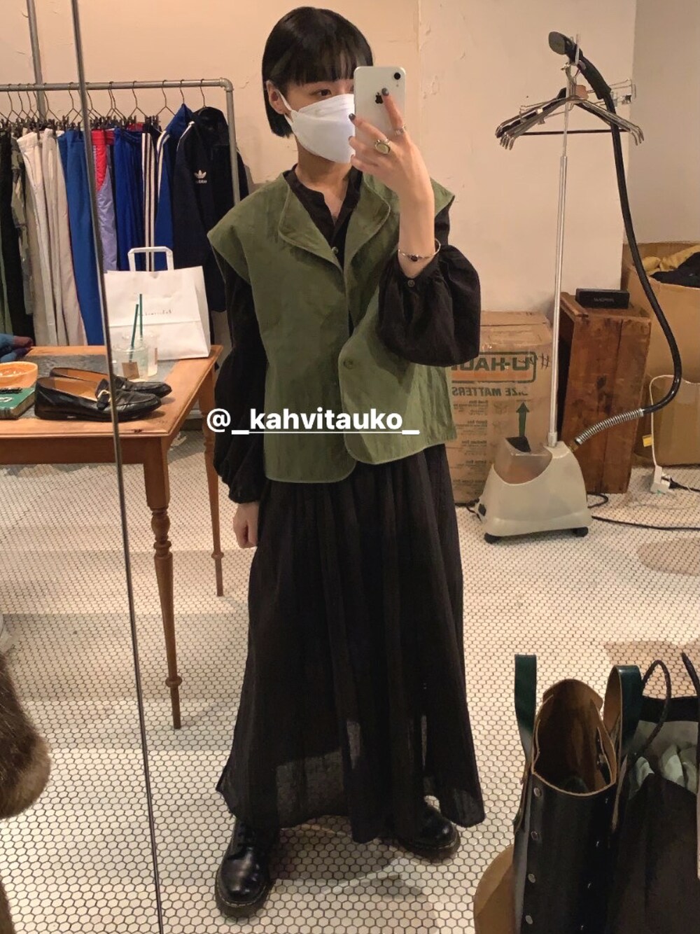 ブラック系のワンピース、グリーン系のベスト、ブラック系のブーツを着用したレディースの秋コーディネートの1枚目の写真