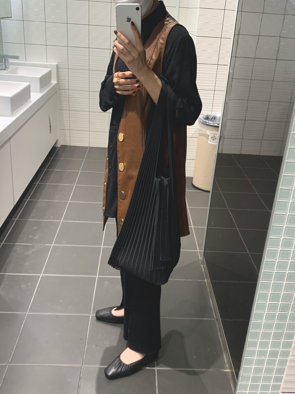 ブラック系のトートバッグ、ブラウン系のベスト、ブラック系のその他パンツを着用したレディースの秋コーディネートの1枚目の写真