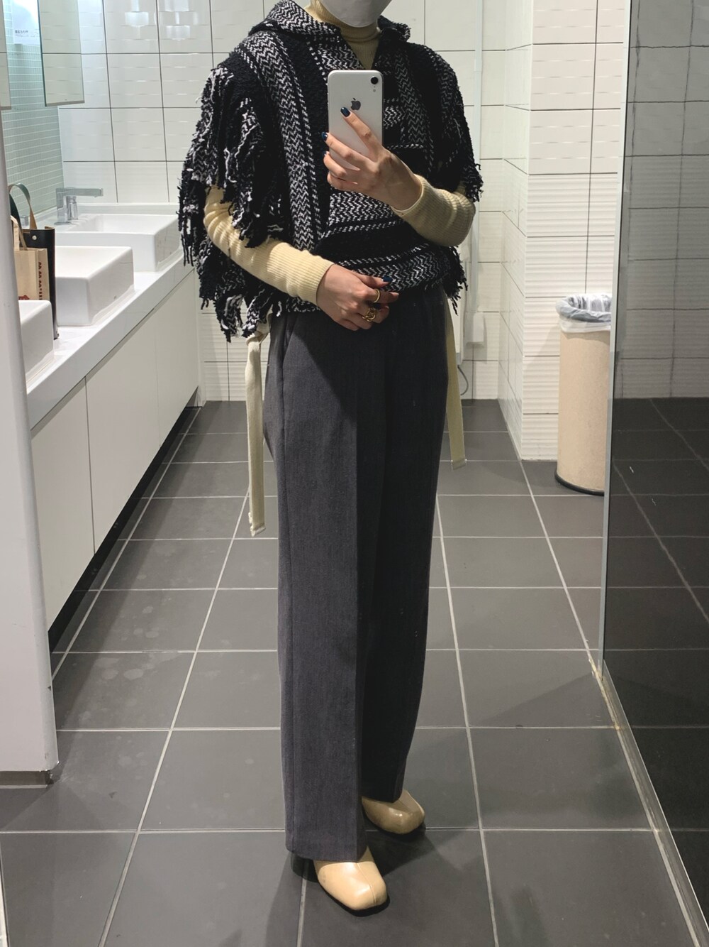 グレー系のスラックス、ベージュ系のブーツ、ブラック系のベストを着用したレディースの秋コーディネートの1枚目の写真