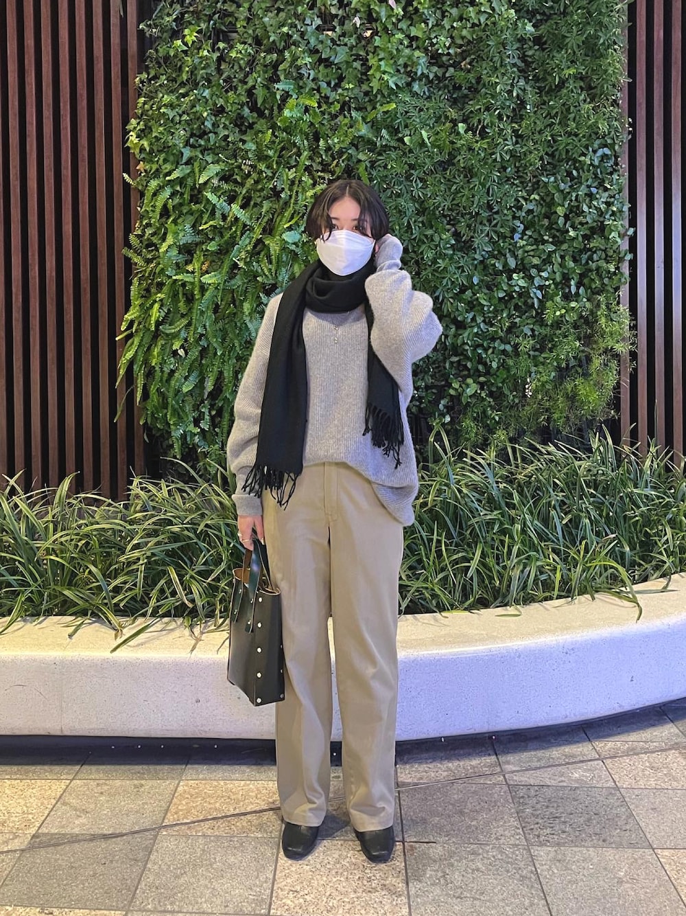 グレー系のニット/セーター、ベージュ系のチノパンツ、ブラック系のハンドバッグを着用したレディースの冬コーディネートの1枚目の写真