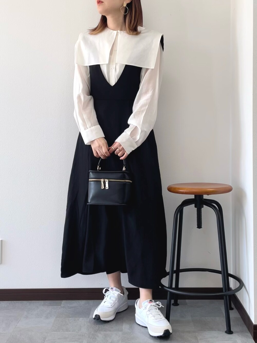 ブラック系のジャンパースカート、ホワイト系のシャツ/ブラウス、ブラック系のショルダーバッグを着用したレディースの春コーディネートの1枚目の写真