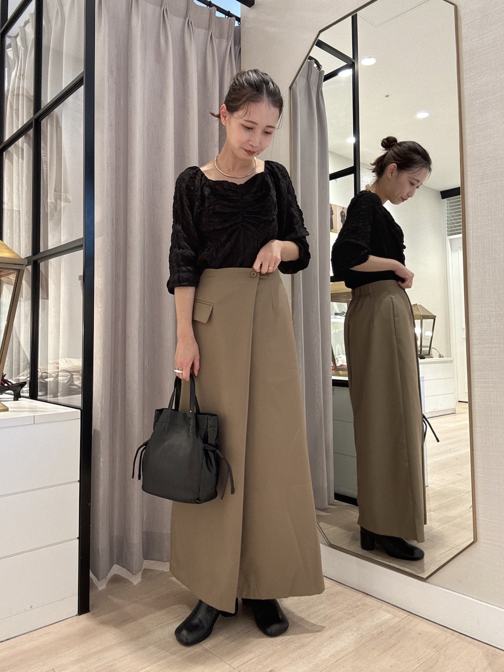 ブラック系のシャツ/ブラウス、ベージュ系のスカート、ブラック系のショルダーバッグを着用したレディースの秋コーディネートの1枚目の写真