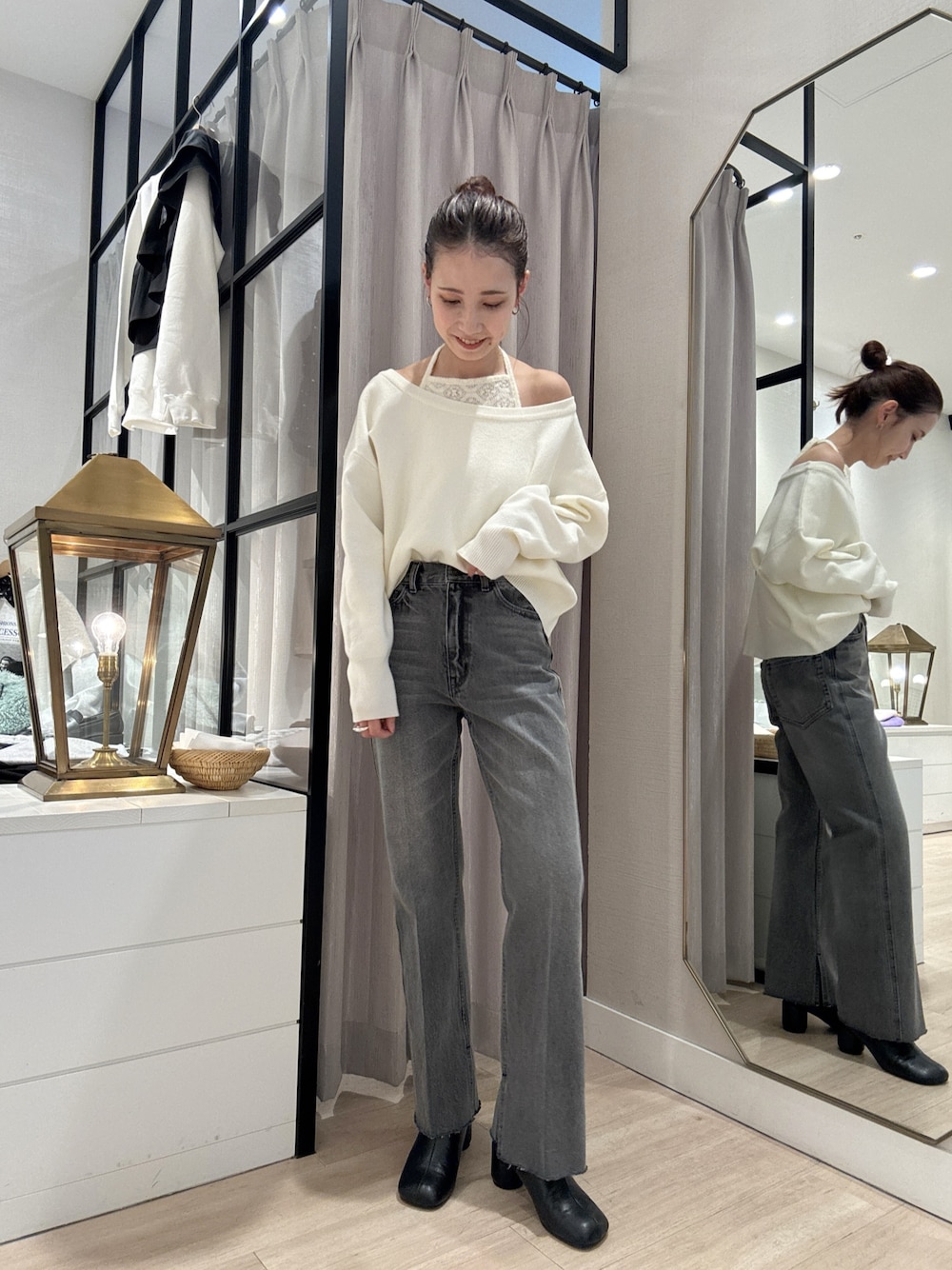 ホワイト系のニット/セーター、ブラック系のデニムパンツ、ブラック系のブーツを着用したレディースの秋コーディネートの1枚目の写真