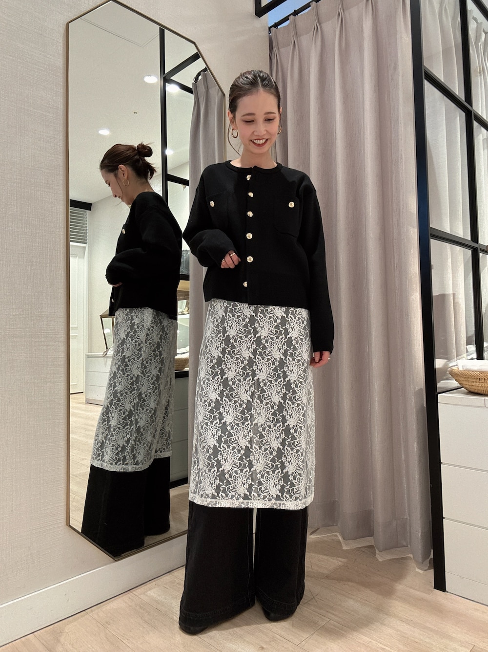 ブラック系のカーディガン/ボレロ、ホワイト系のスカート、グレー系のデニムパンツを着用したレディースの冬コーディネートの1枚目の写真