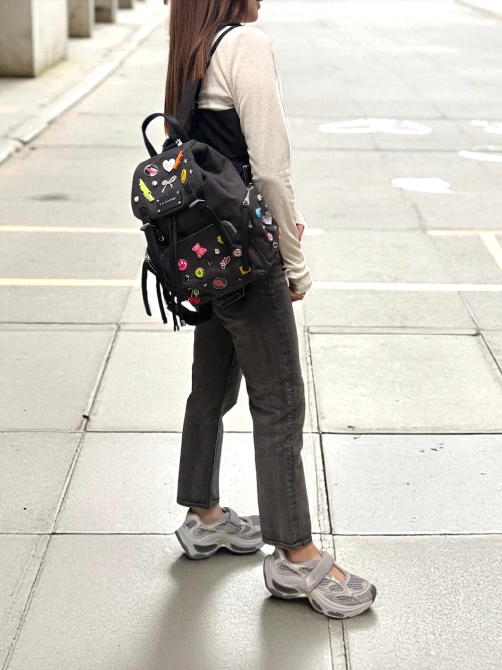 グレー系のスニーカー、グレー系のデニムパンツ、ブラック系のトップスを着用したレディースの秋コーディネートの1枚目の写真