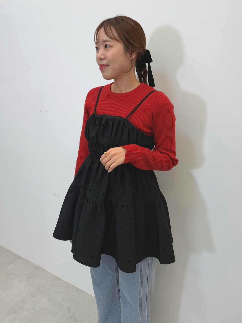 ブラック系のキャミソール、レッド系のニット/セーター、ブルー系のデニムパンツを着用したレディースの秋コーディネートの1枚目の写真