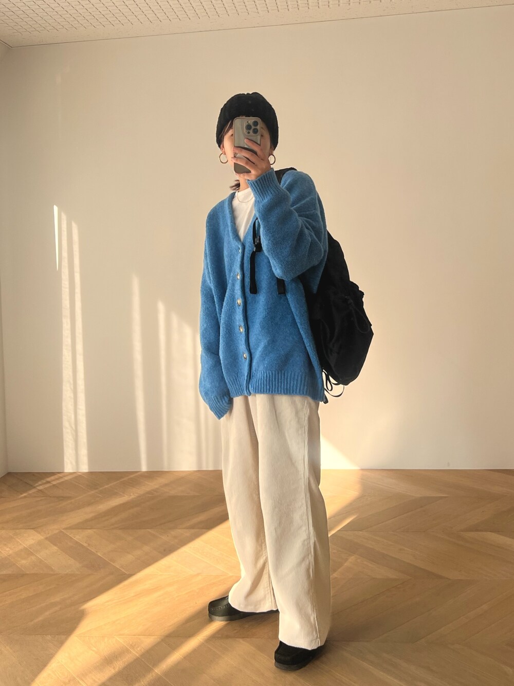 ベージュ系のその他パンツ、ブルー系のカーディガン/ボレロ、ブラック系のバックパック/リュックを着用したレディースの冬コーディネートの1枚目の写真