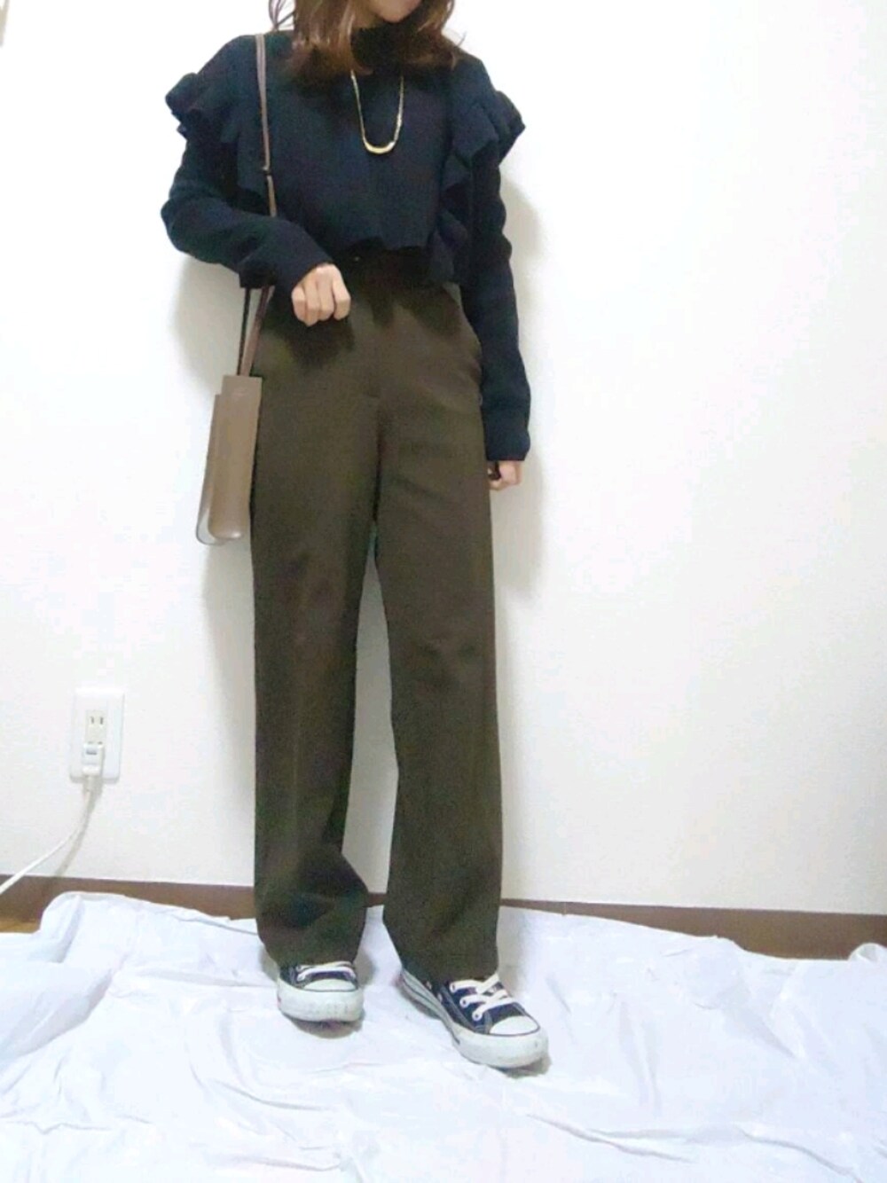 ベージュ系のパンツ、ブラック系のスニーカー、ブラック系のニット/セーターを着用したレディースの秋コーディネートの1枚目の写真