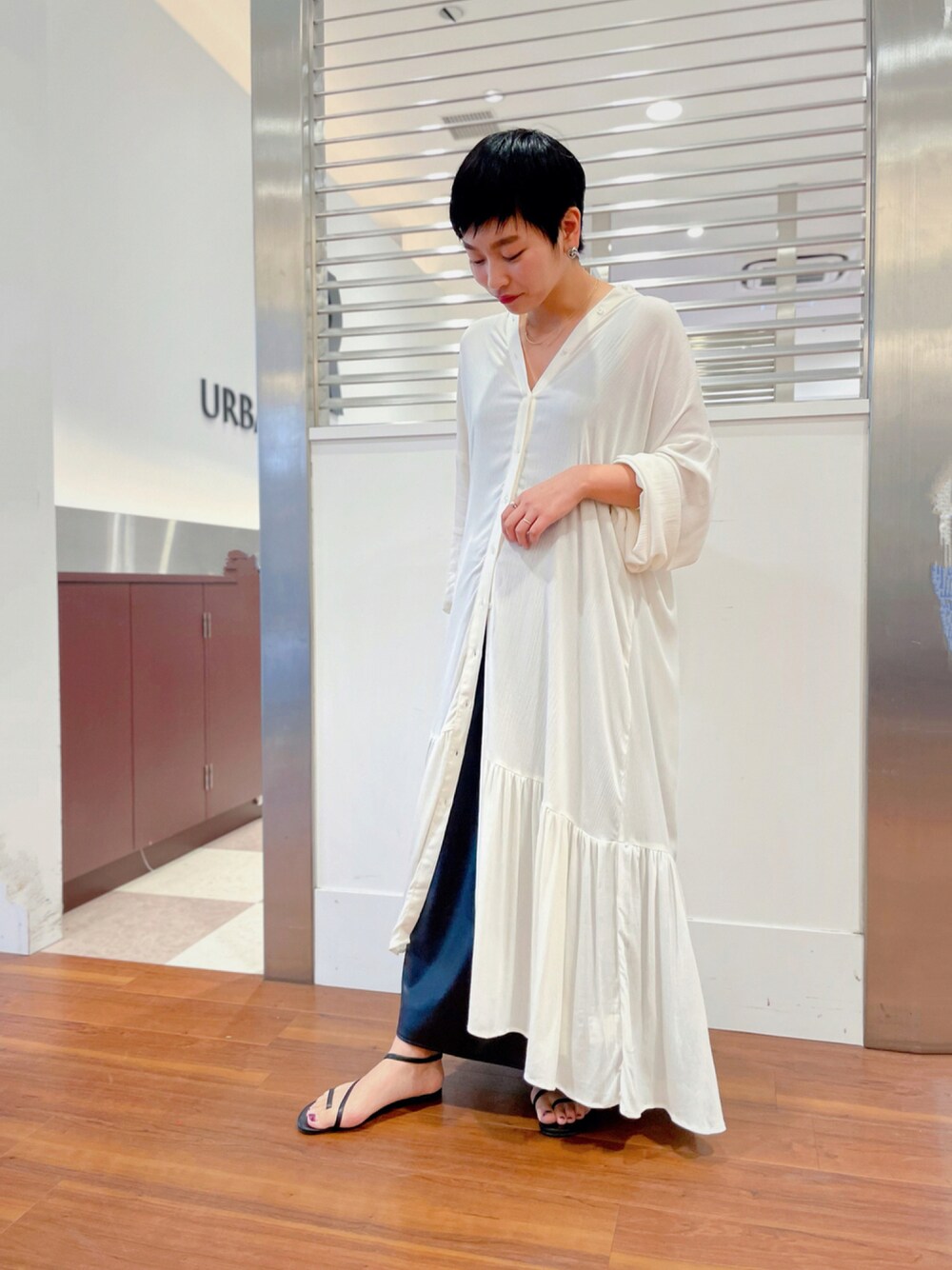 ホワイト系のワンピース、ブラック系のスカート、ブラック系のサンダルを着用したレディースの秋コーディネートの1枚目の写真