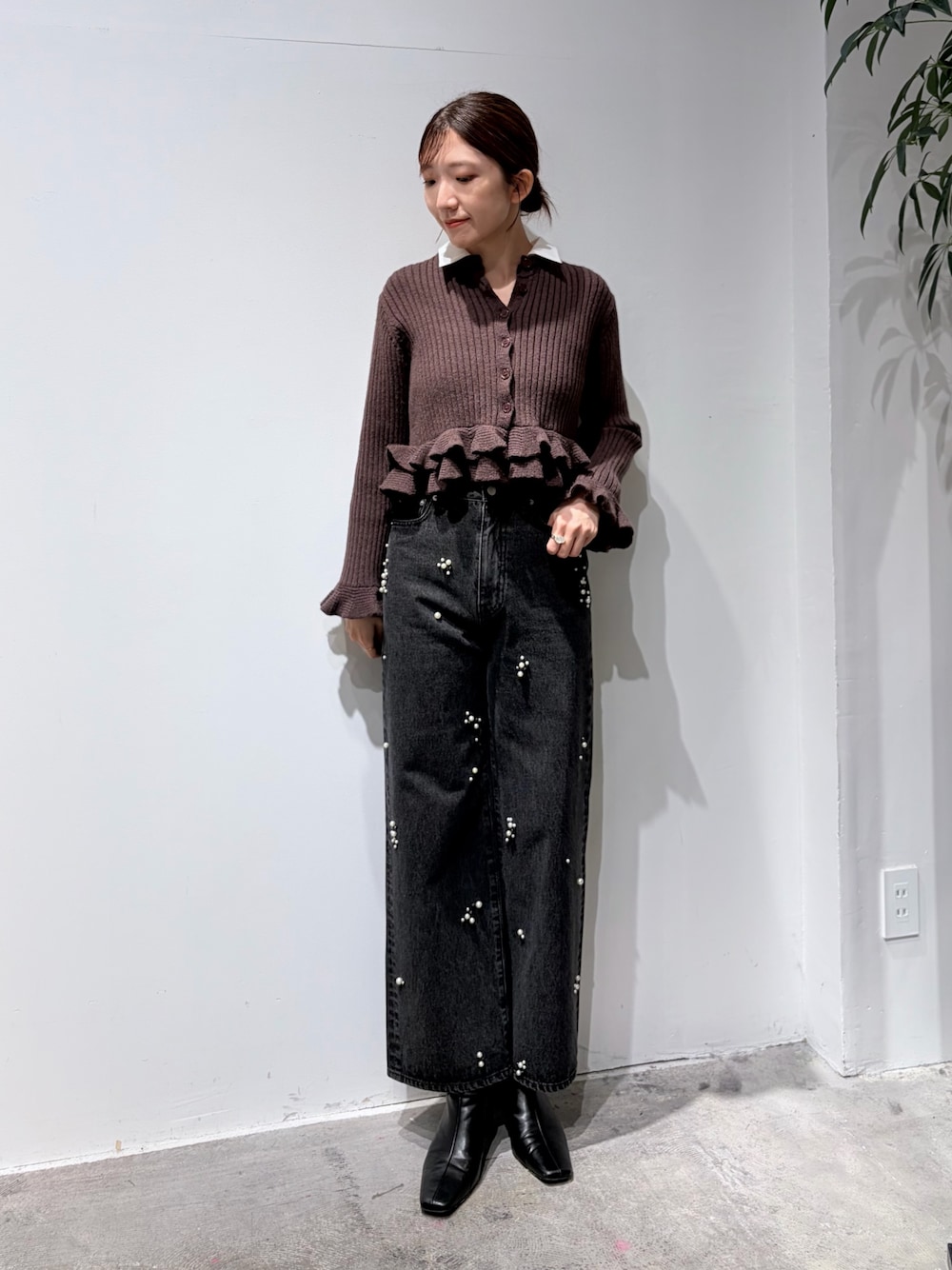 ブラック系のデニムパンツ、ブラウン系のニット/セーター、ブラック系のブーツを着用したレディースの秋コーディネートの1枚目の写真