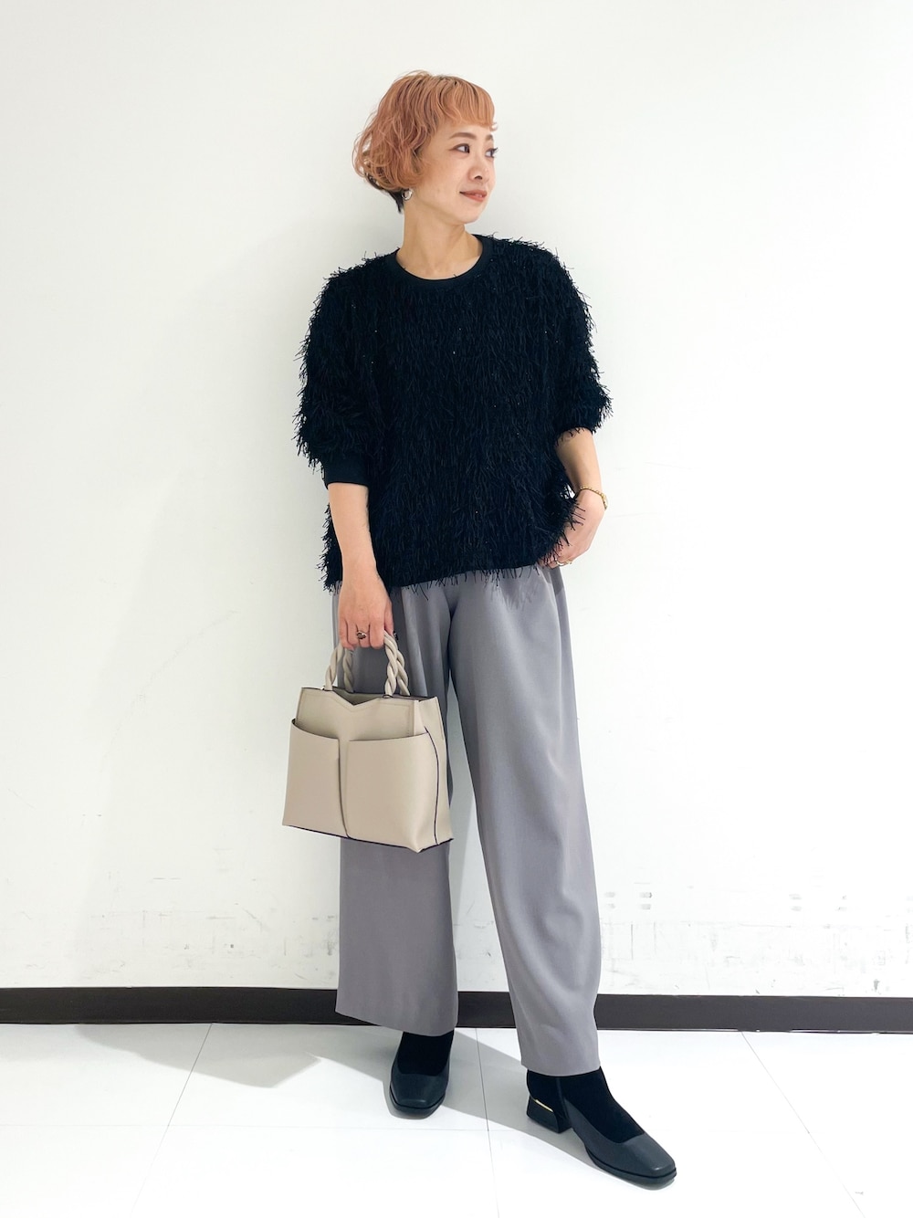 ベージュ系のショルダーバッグ、ブラック系のブーツを着用したレディースの冬コーディネートの1枚目の写真