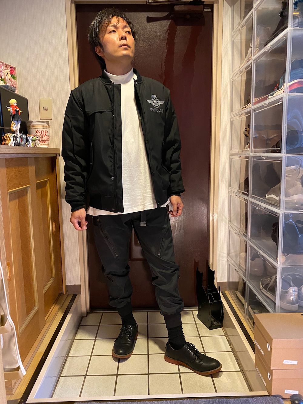 ブラック系のスタジャン、ホワイト系のTシャツ/カットソー、ブラック系のカーゴパンツを着用したメンズの冬コーディネートの1枚目の写真