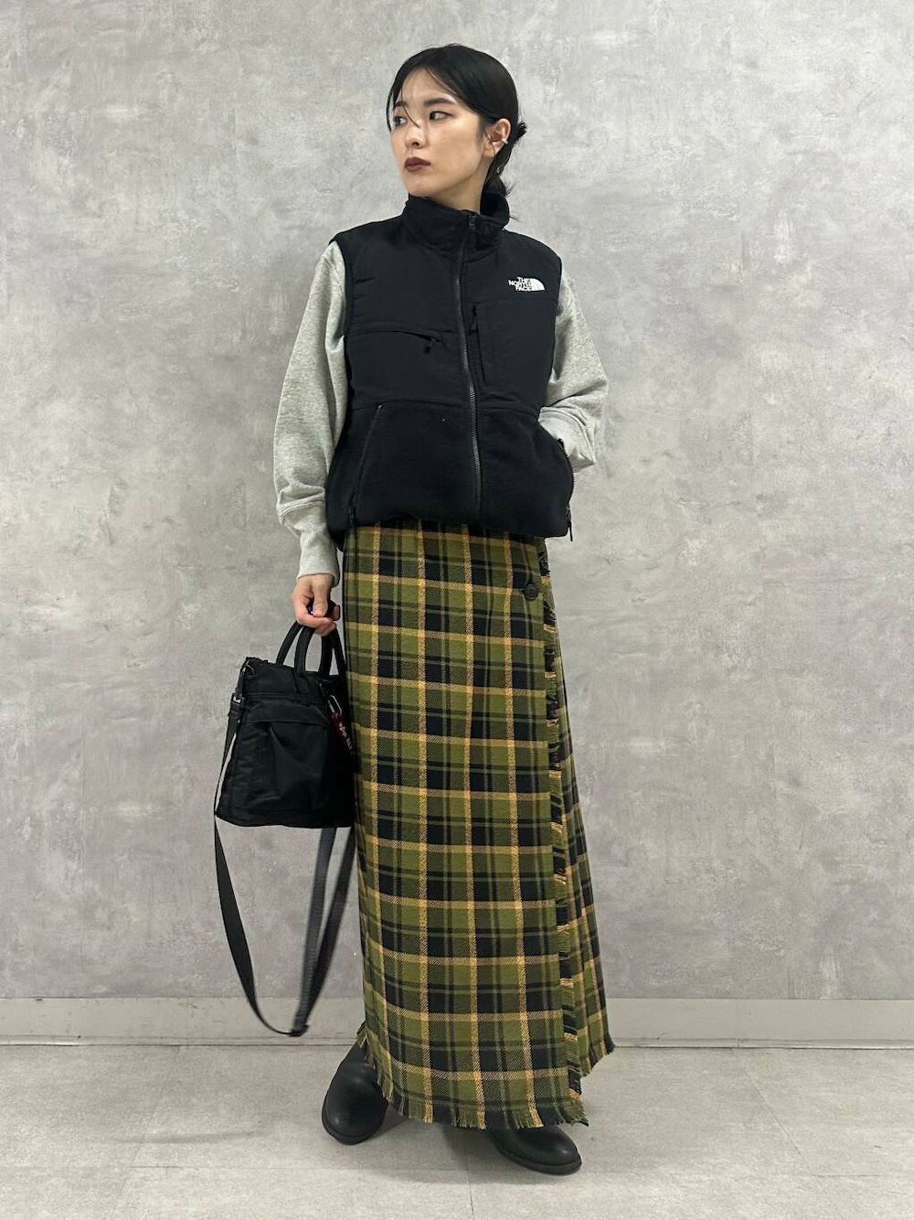 ブラック系のショルダーバッグ、グリーン系のスカート、グレー系のTシャツ/カットソーを着用したレディースの秋コーディネートの1枚目の写真