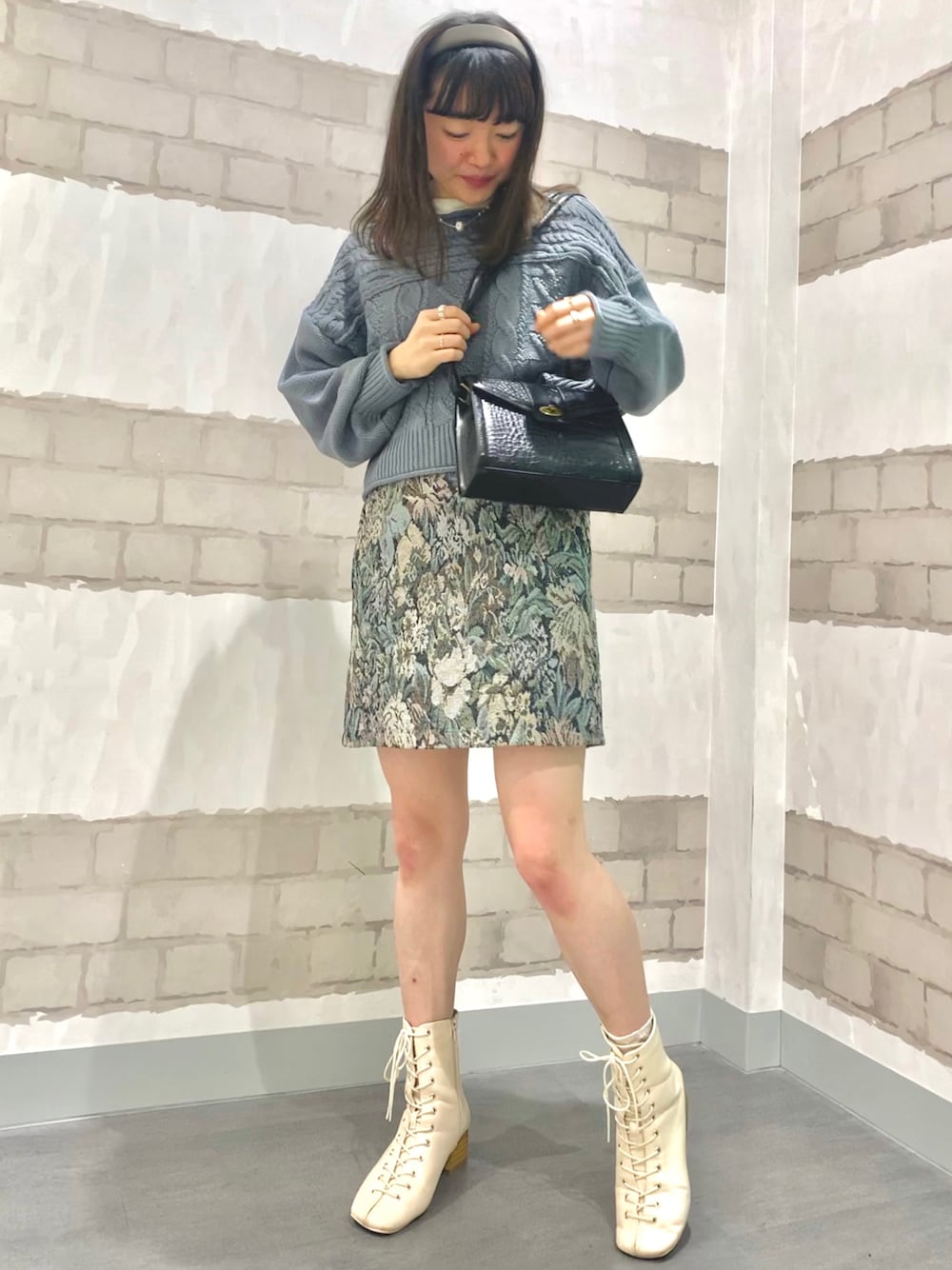 グレー系のスカート、ブルー系のニット/セーター、ホワイト系のTシャツ/カットソーを着用したレディースの秋コーディネートの1枚目の写真