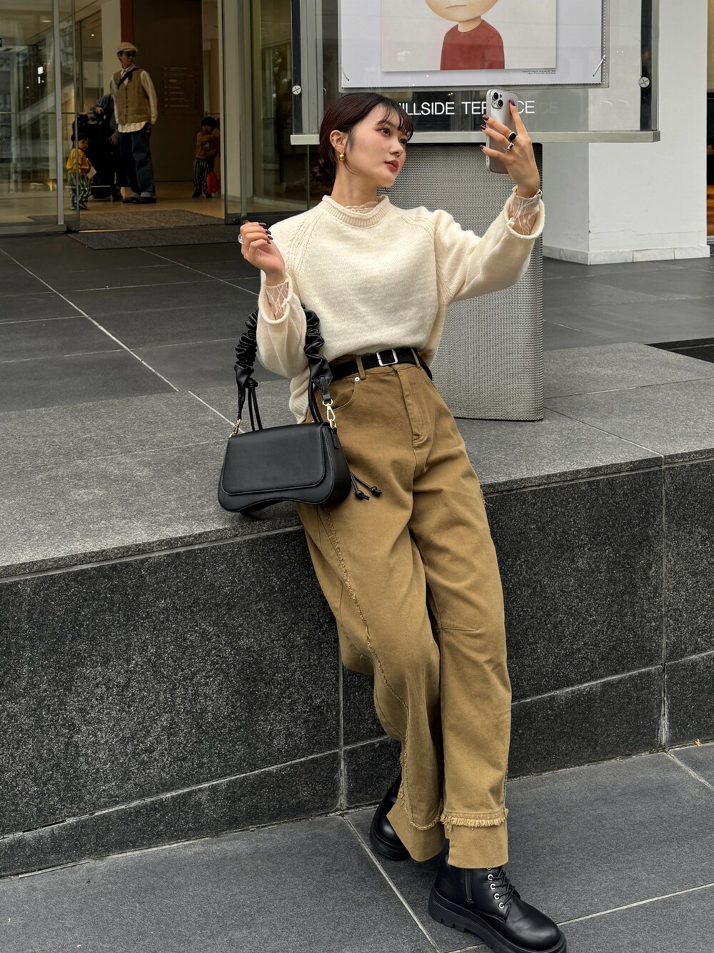 ブラウン系のハンドバッグ、ホワイト系のニット/セーターを着用したレディースの秋コーディネートの1枚目の写真