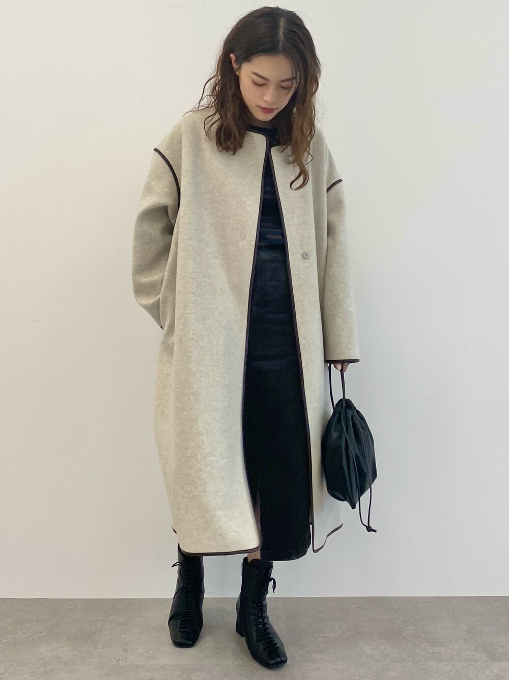 ベージュ系のジャケット/アウター、ブラック系のクラッチバッグ、グレー系のスカートを着用したレディースの秋コーディネートの1枚目の写真