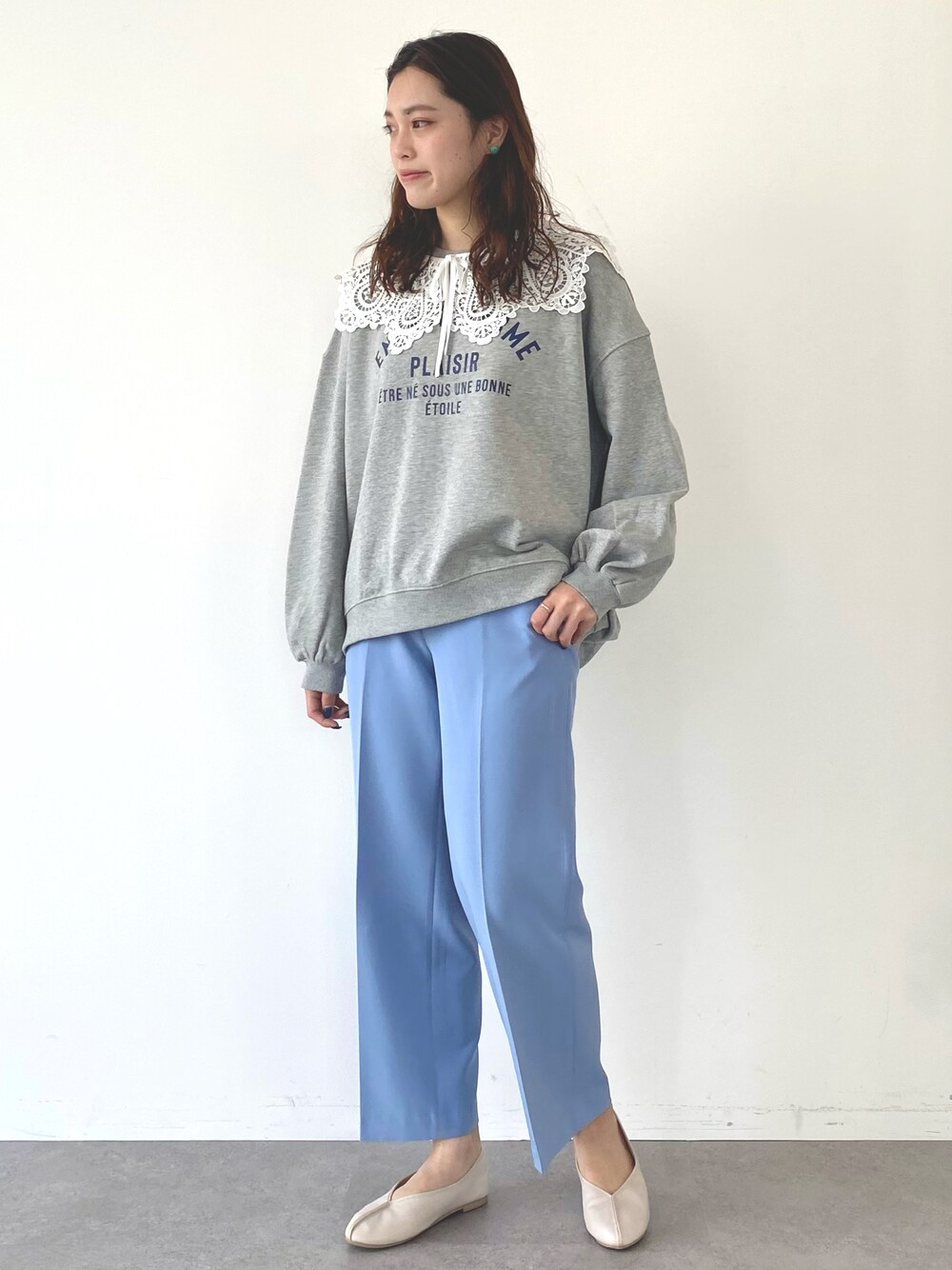 グレー系のスウェット、ブルー系のパンツ、ホワイト系のパンプスを着用したレディースの冬コーディネートの1枚目の写真