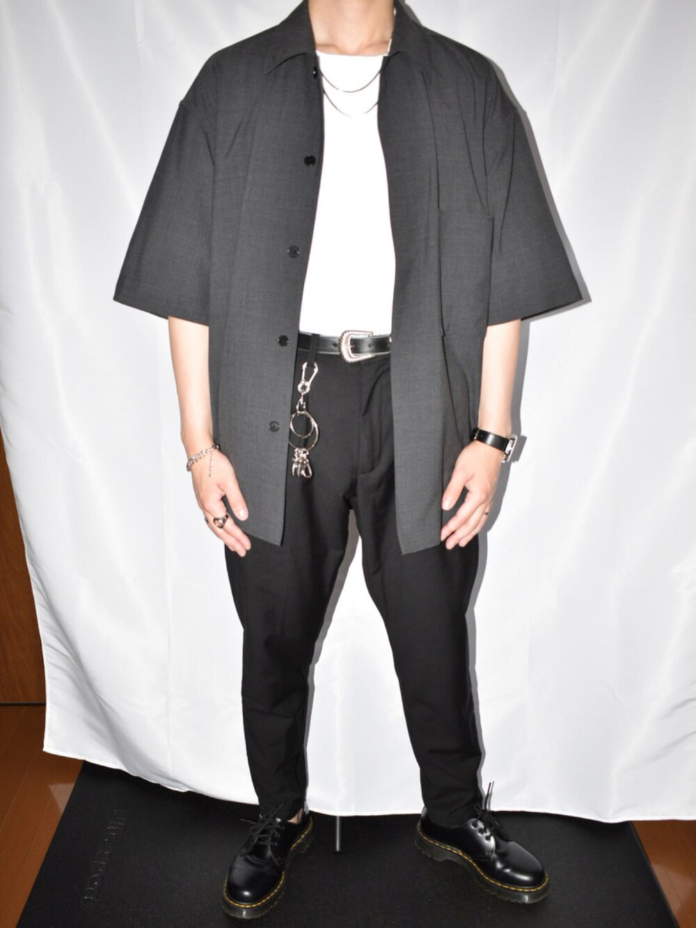 ブラック系のスラックス、ブラック系のブーツ、ホワイト系のTシャツ/カットソーを着用したメンズの夏コーディネートの1枚目の写真