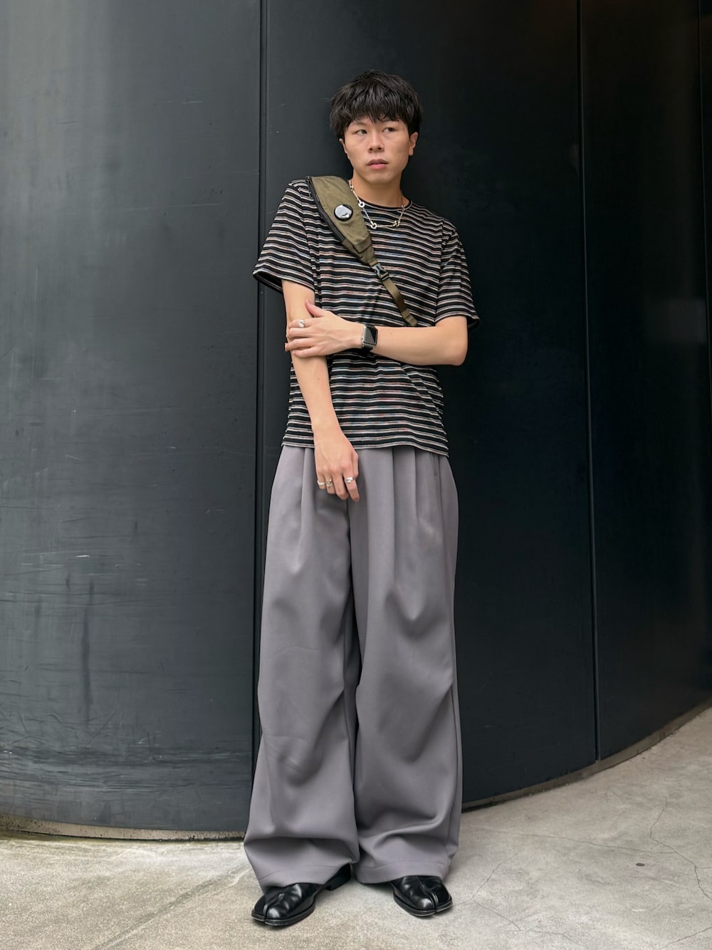 ブラック系のTシャツ/カットソー、グレー系のパンツ、グリーン系のバックパック/リュックを着用したメンズの夏コーディネートの1枚目の写真