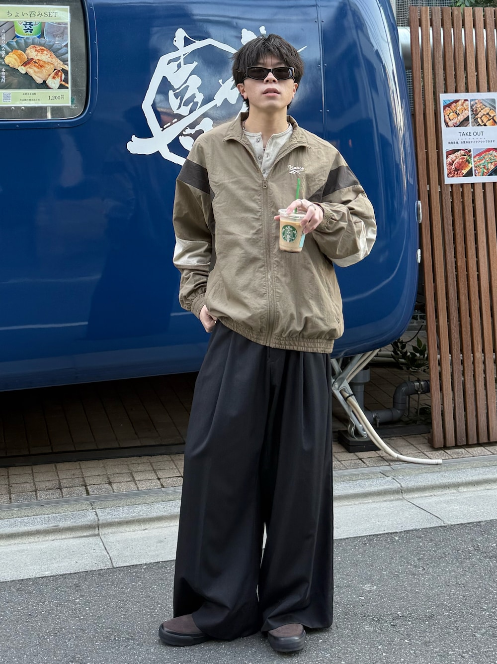 ベージュ系のナイロンジャケット、ベージュ系のTシャツ/カットソー、グレー系のスラックスを着用したメンズの春コーディネートの1枚目の写真