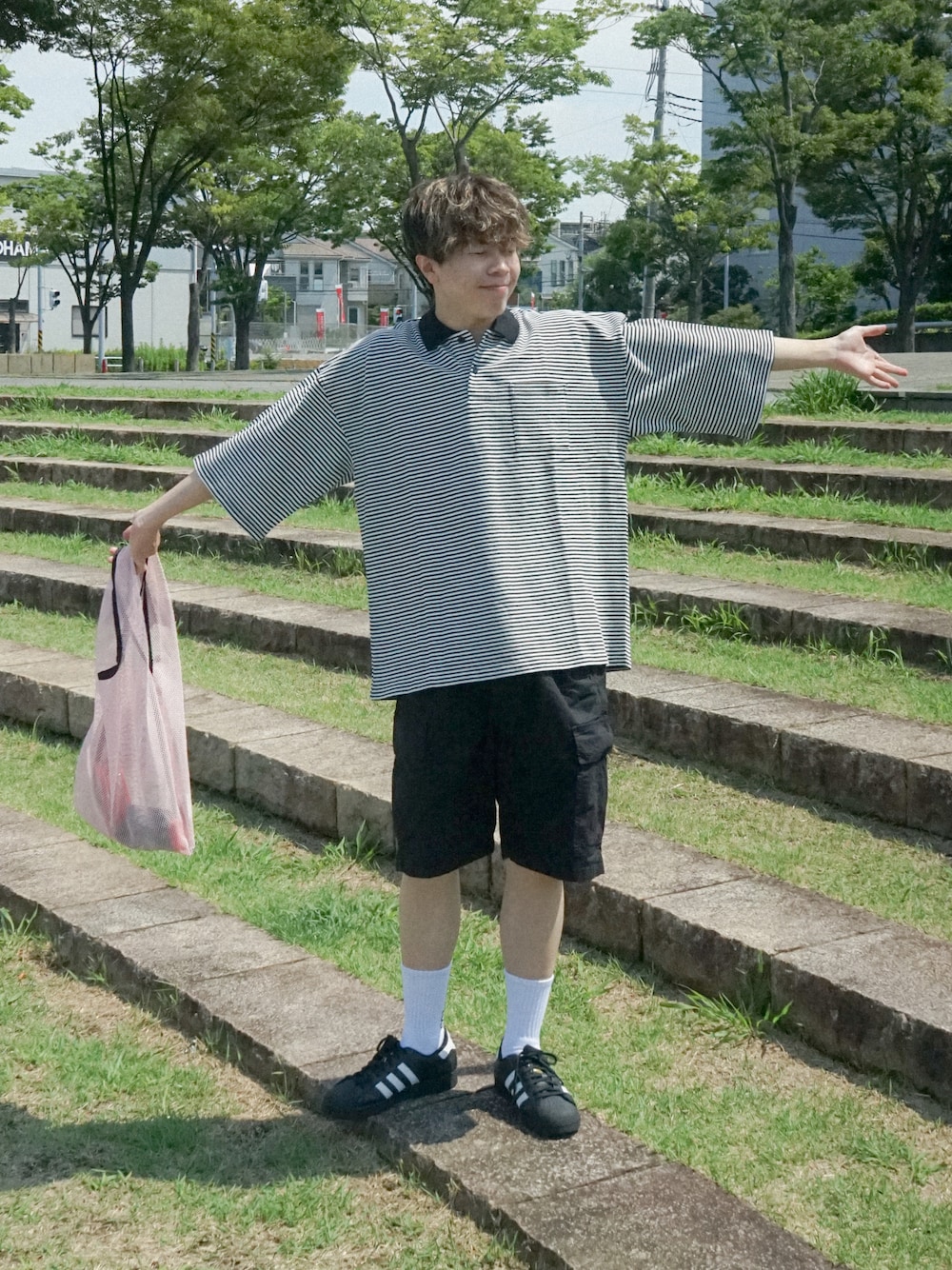 ピンク系のトートバッグ、ブラック系のスニーカー、ブルー系のその他を着用したメンズの夏コーディネートの1枚目の写真