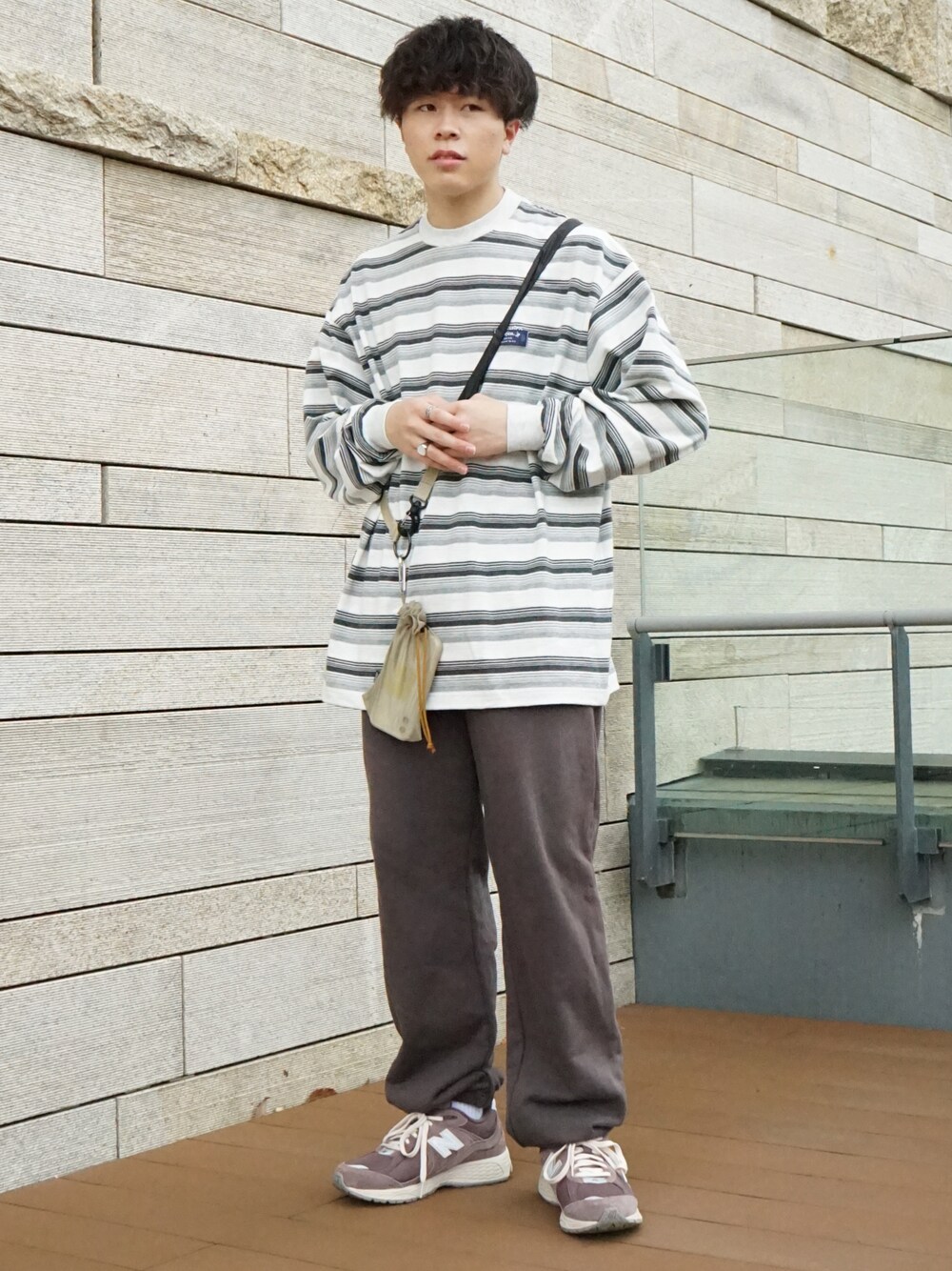 グレー系のTシャツ/カットソー、グレー系のスウェットパンツ、ベージュ系のショルダーバッグを着用したメンズの春コーディネートの1枚目の写真