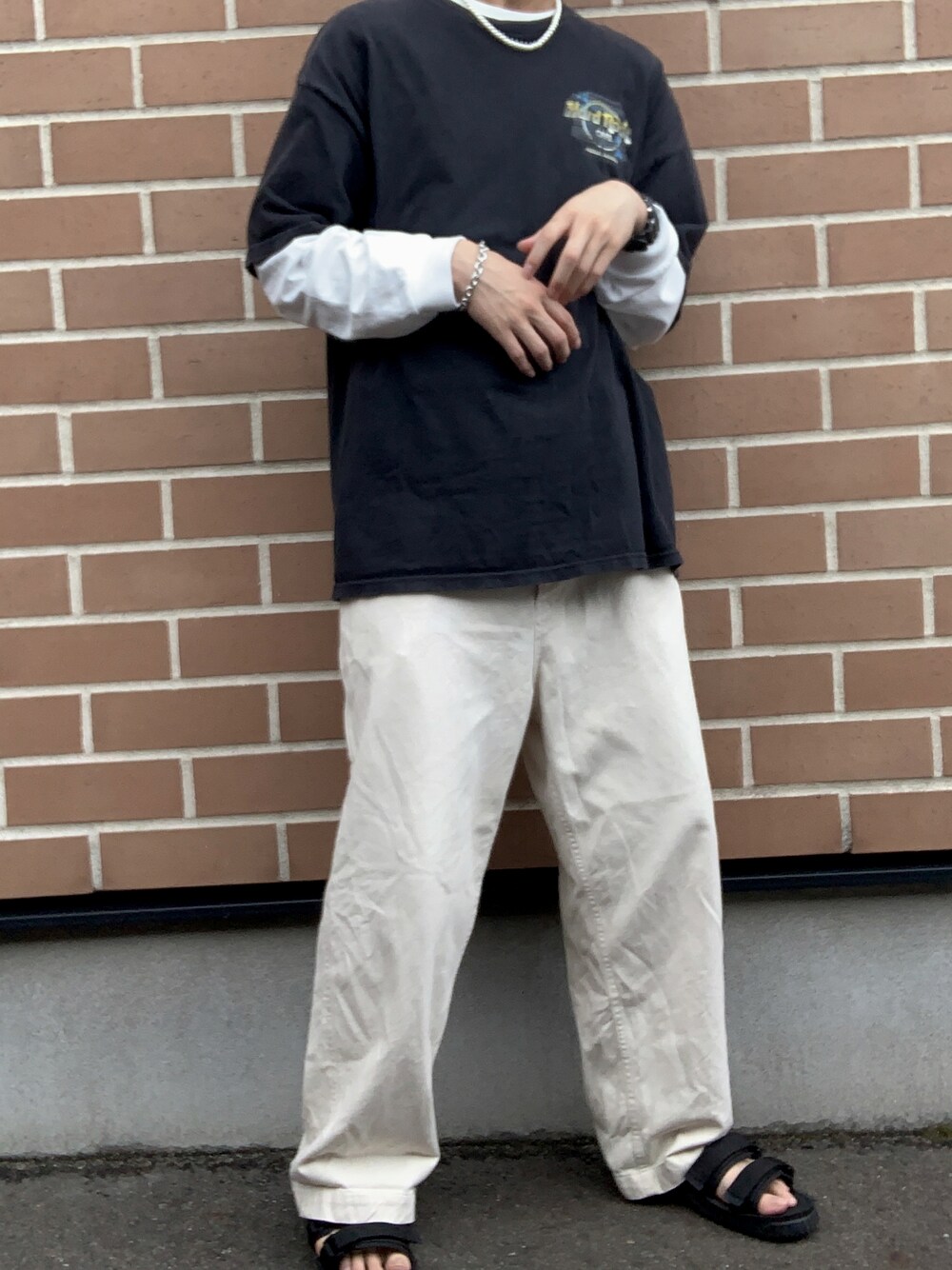 ブラック系のサンダル、ホワイト系のパンツ、ブラック系のTシャツ/カットソーを着用したメンズの秋コーディネートの1枚目の写真