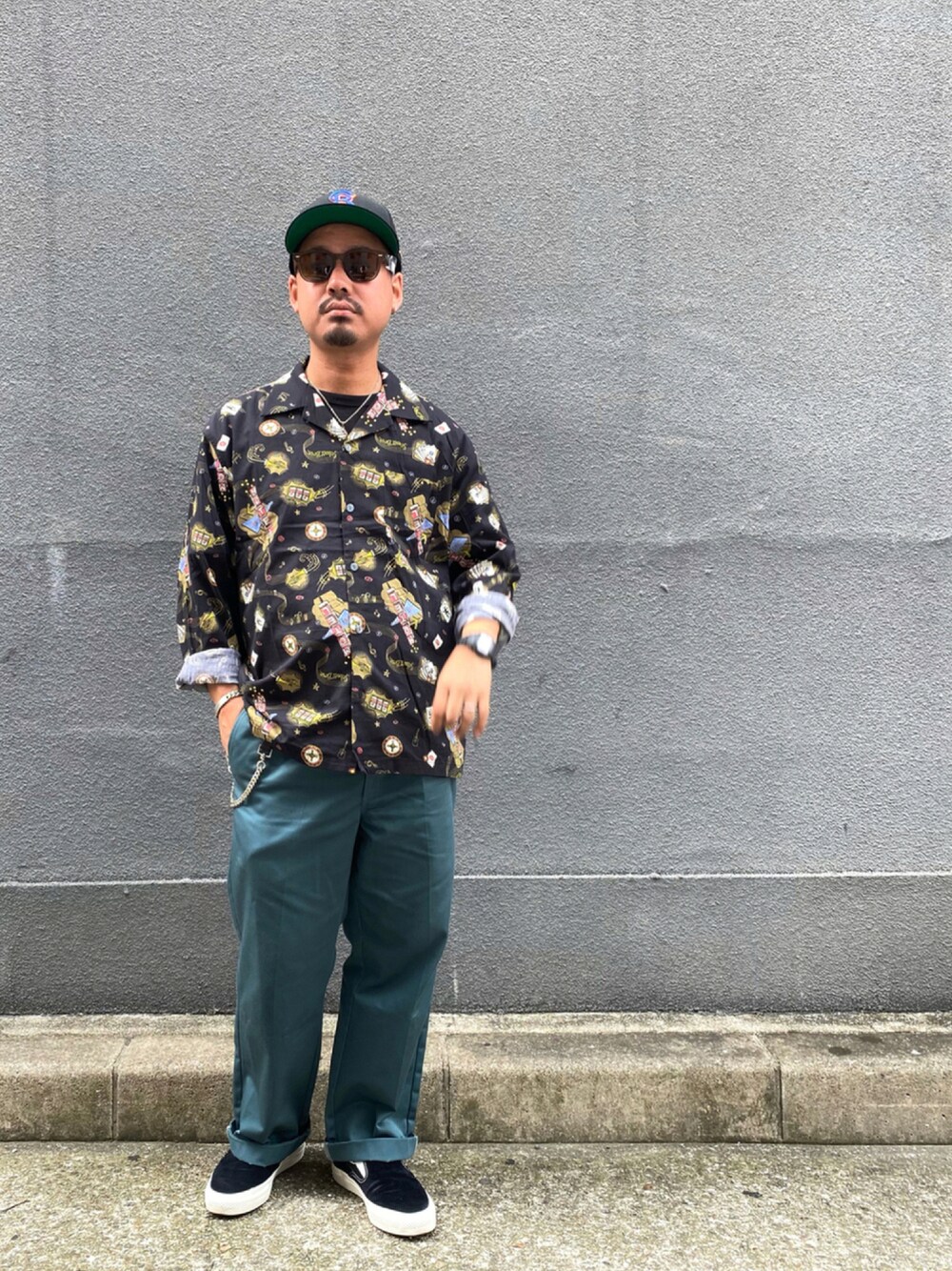 グリーン系のチノパンツ、ブラック系のスリッポンを着用したメンズの夏コーディネートの1枚目の写真