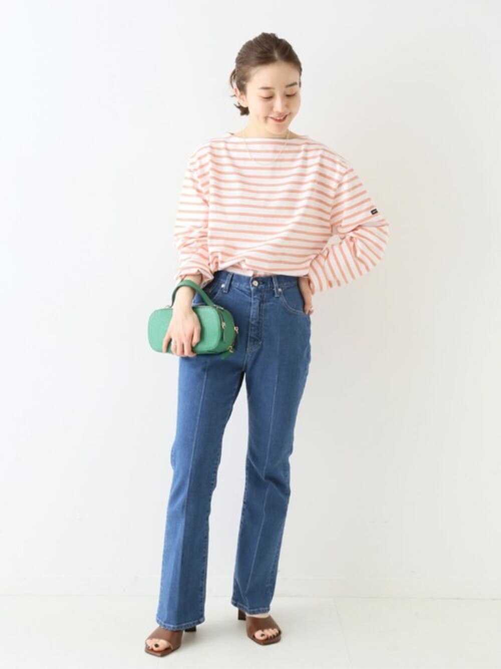 グリーン系のショルダーバッグ、シルバー系のネックレスを着用したレディースの冬コーディネートの1枚目の写真