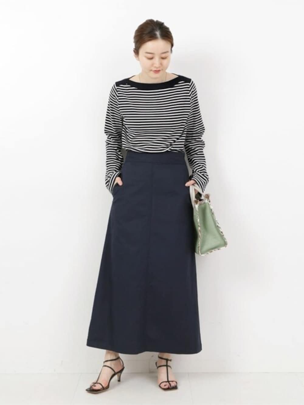 グリーン系のハンドバッグ、ブルー系のTシャツ/カットソー、シルバー系のネックレスを着用したレディースの春コーディネートの1枚目の写真