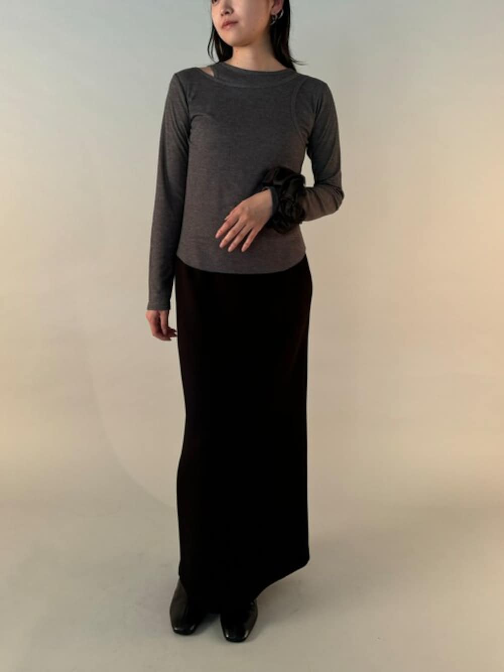 ブラック系のスカート、グレー系のTシャツ/カットソー、ゴールド系のイヤーカフを着用したレディースの秋コーディネートの1枚目の写真