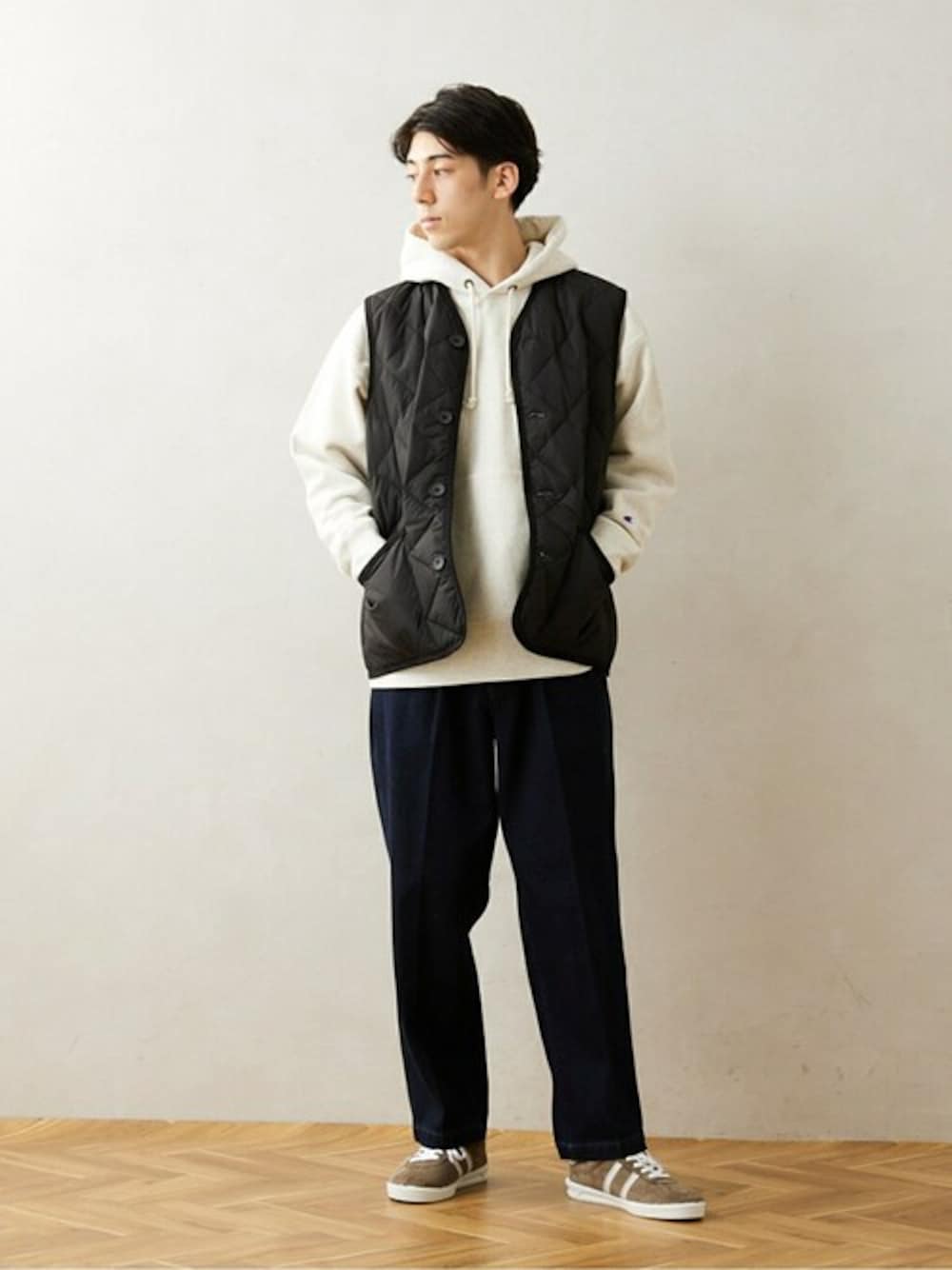 ブラック系のダウンベスト、ホワイト系のパーカー、ブルー系のデニムパンツを着用したメンズの冬コーディネートの1枚目の写真