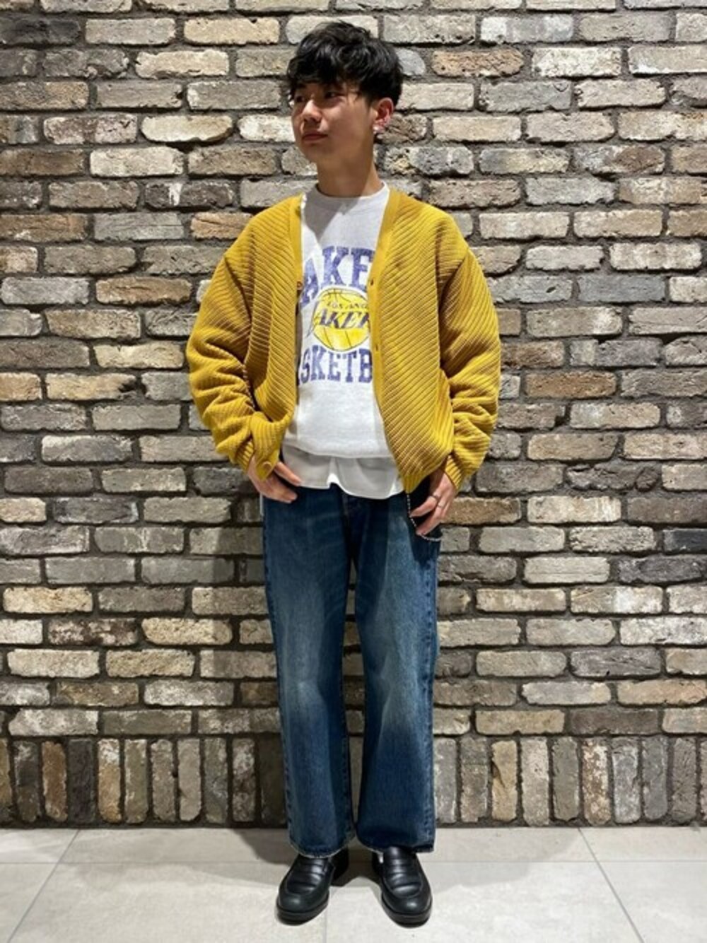 イエロー系のニット/セーター、グレー系のスウェット、ブルー系のデニムパンツを着用したメンズの冬コーディネートの1枚目の写真