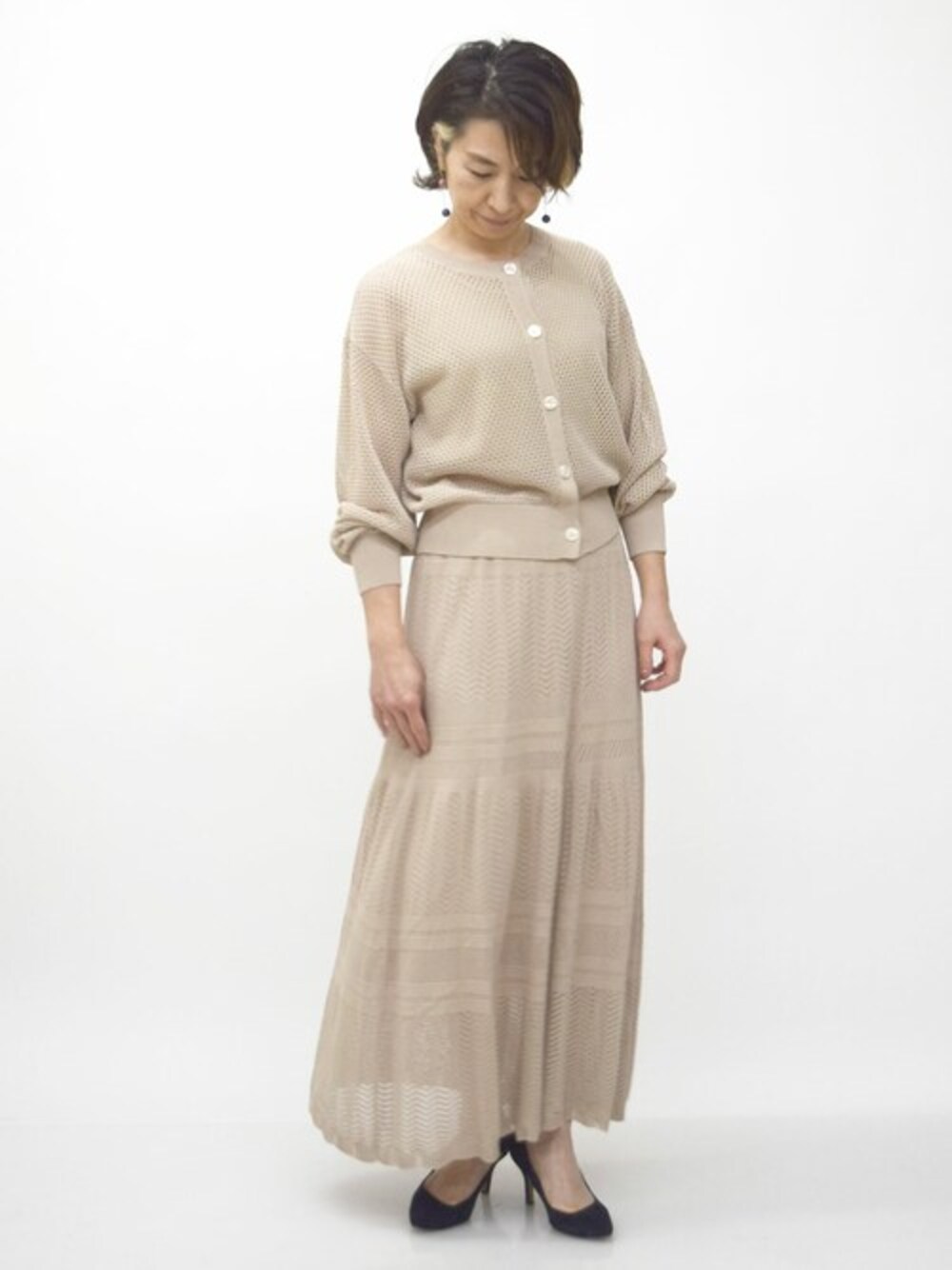 ベージュ系のスカート、ベージュ系のカーディガン/ボレロを着用したレディースの春コーディネートの1枚目の写真