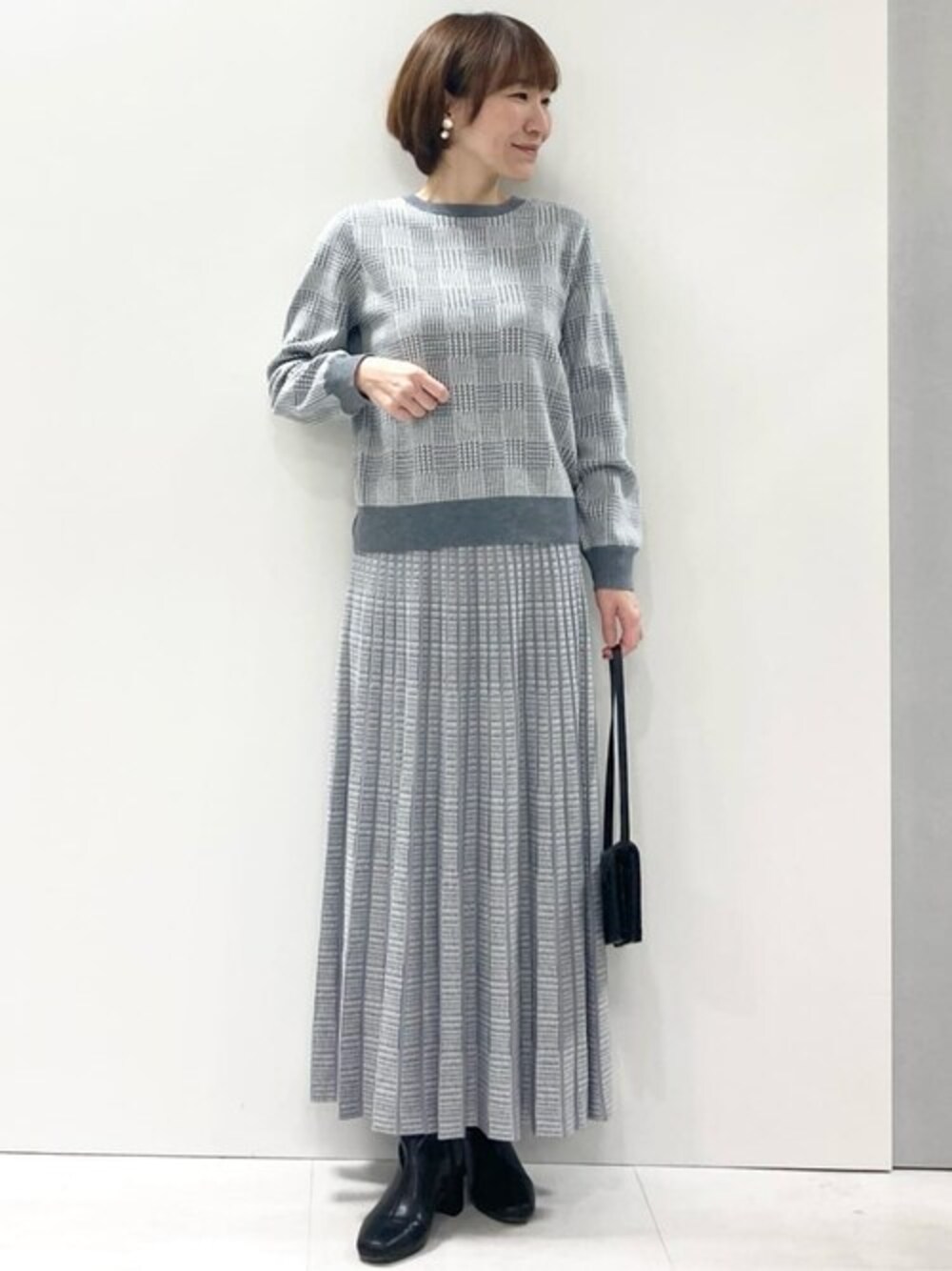 グレー系のニット/セーター、グレー系のスカートを着用したレディースの冬コーディネートの1枚目の写真