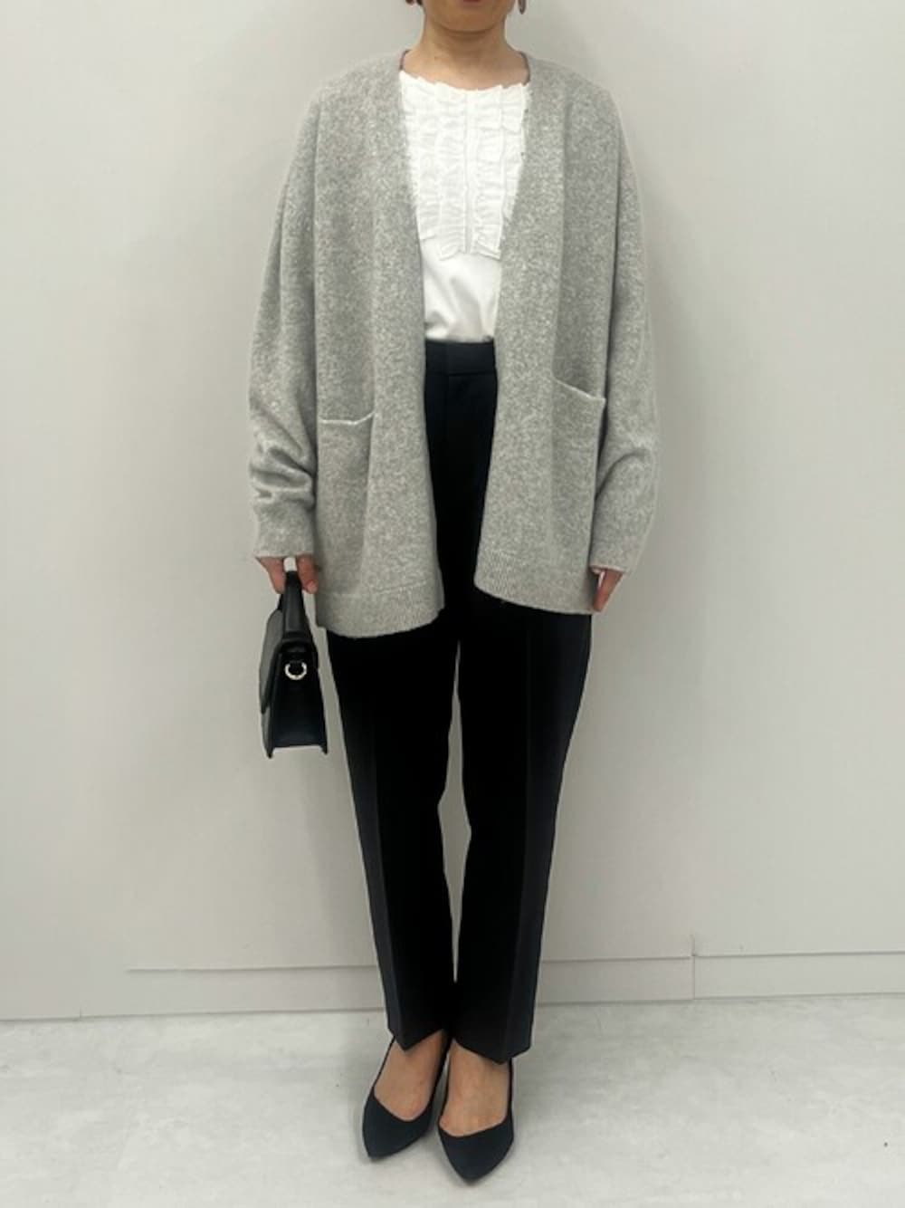 グレー系のカーディガン/ボレロ、ホワイト系のTシャツ/カットソー、グレー系のスラックスを着用したレディースの秋コーディネートの1枚目の写真