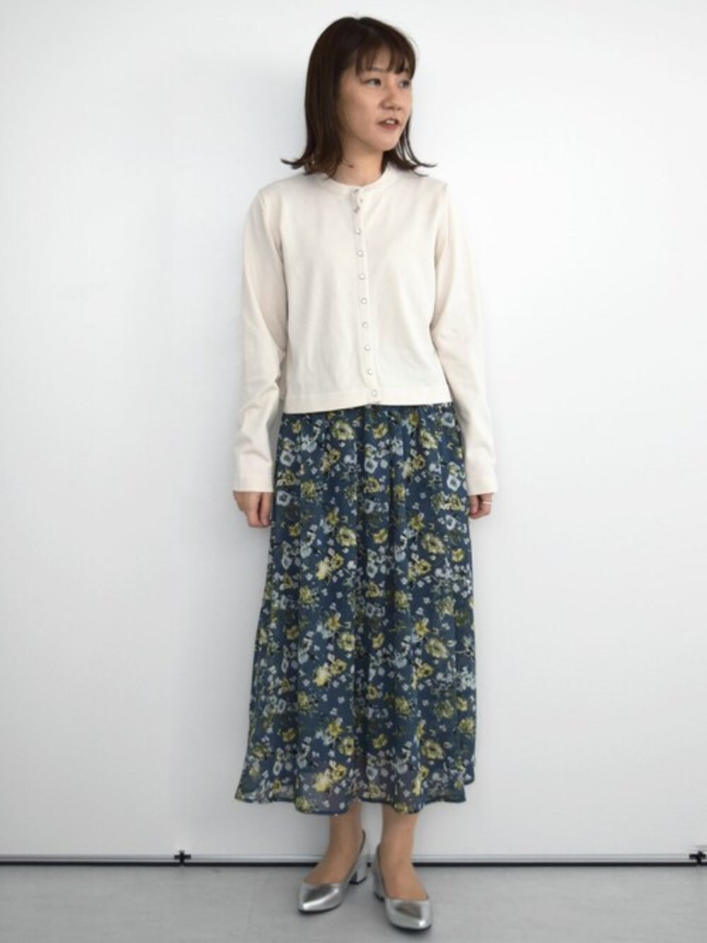 ホワイト系のカーディガン/ボレロ、ブルー系のスカートを着用したレディースの秋コーディネートの1枚目の写真