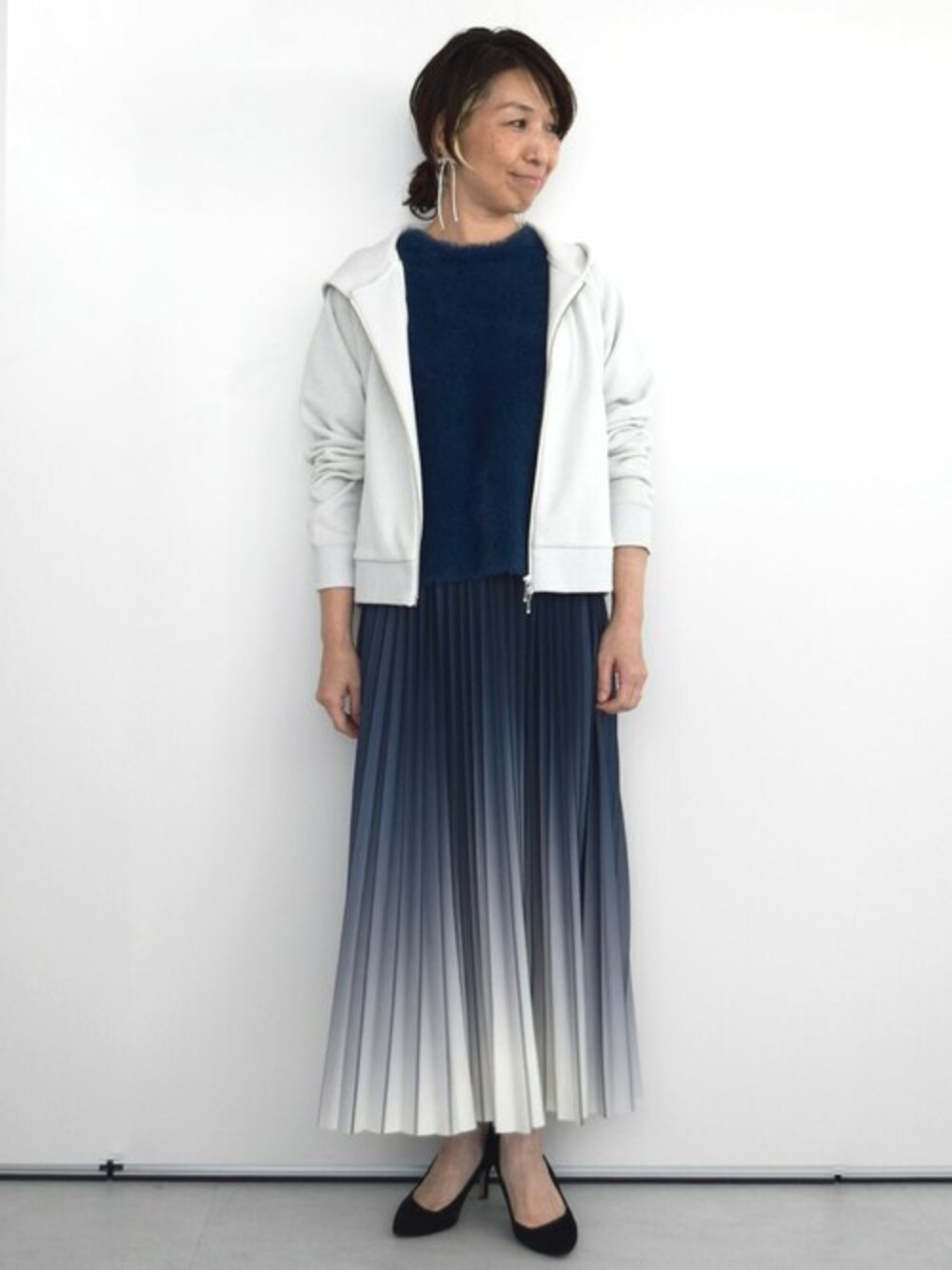 グレー系のパーカー、ブルー系のニット/セーター、ブルー系のスカートを着用したレディースの秋コーディネートの1枚目の写真