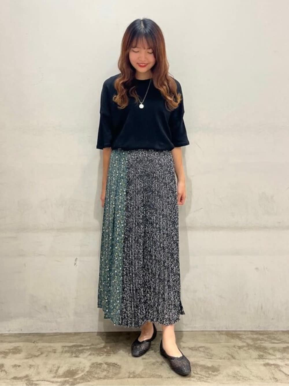 ブラック系のTシャツ/カットソー、グリーン系のスカート、ブラック系のパンプスを着用したレディースの夏コーディネートの1枚目の写真