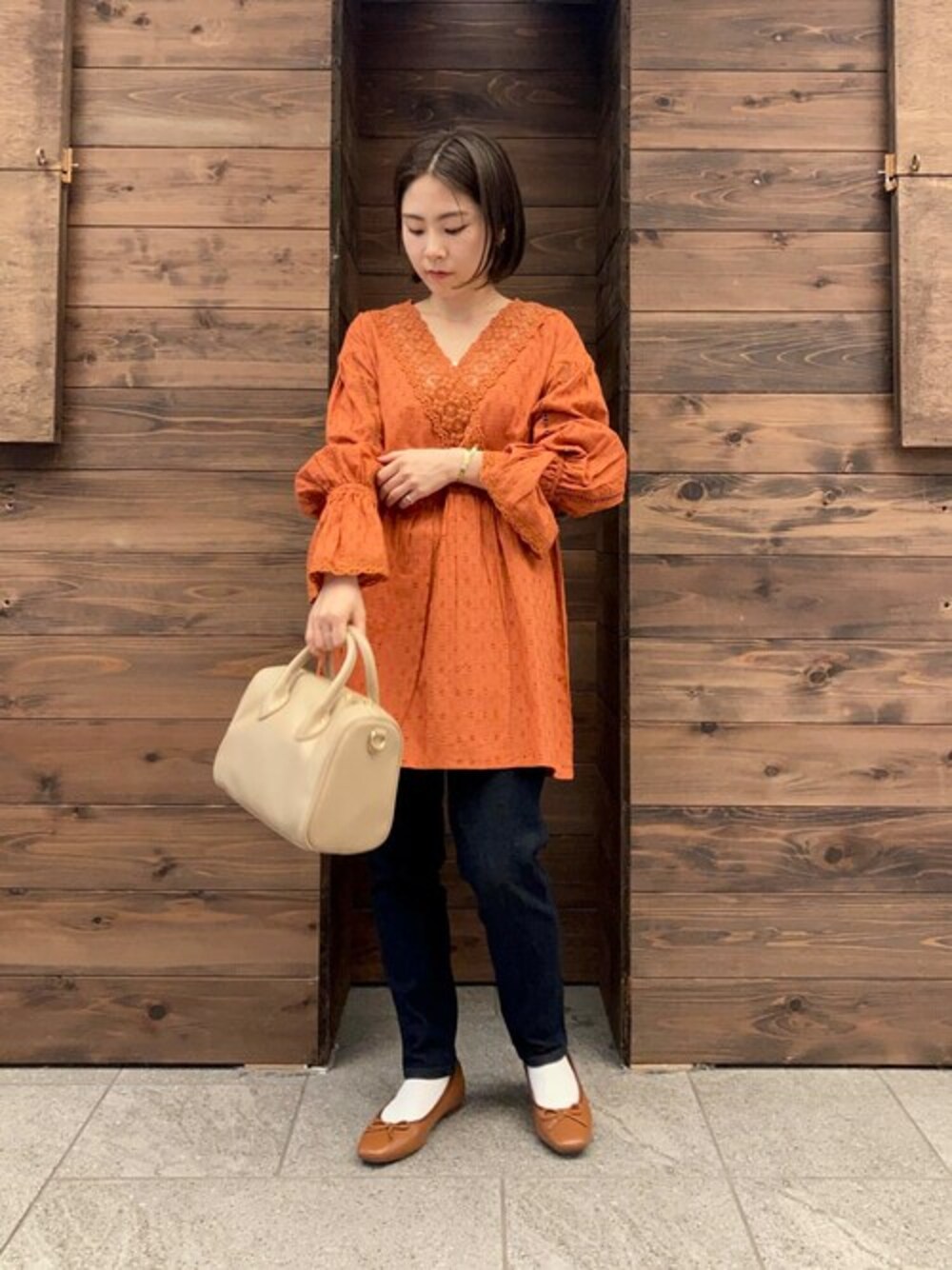 レッド系のシャツ/ブラウス、ブルー系のデニムパンツ、ベージュ系のハンドバッグを着用したレディースの秋コーディネートの1枚目の写真